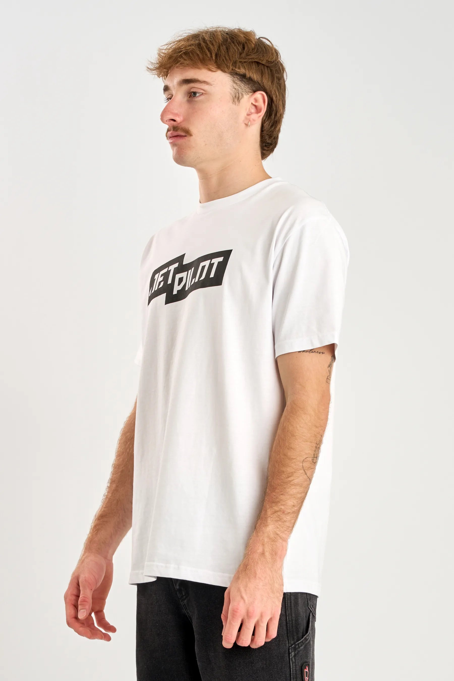 Person wearing a white t-shirt with a logo on a plain background