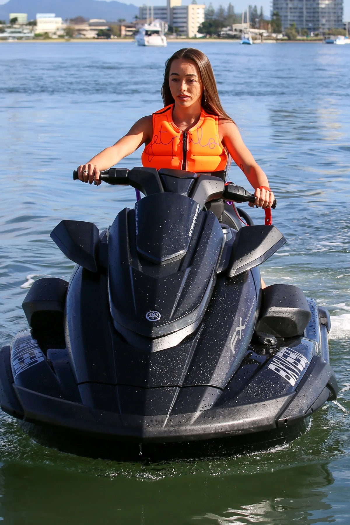 Person riding a jet ski on a body of water with buildings in the background