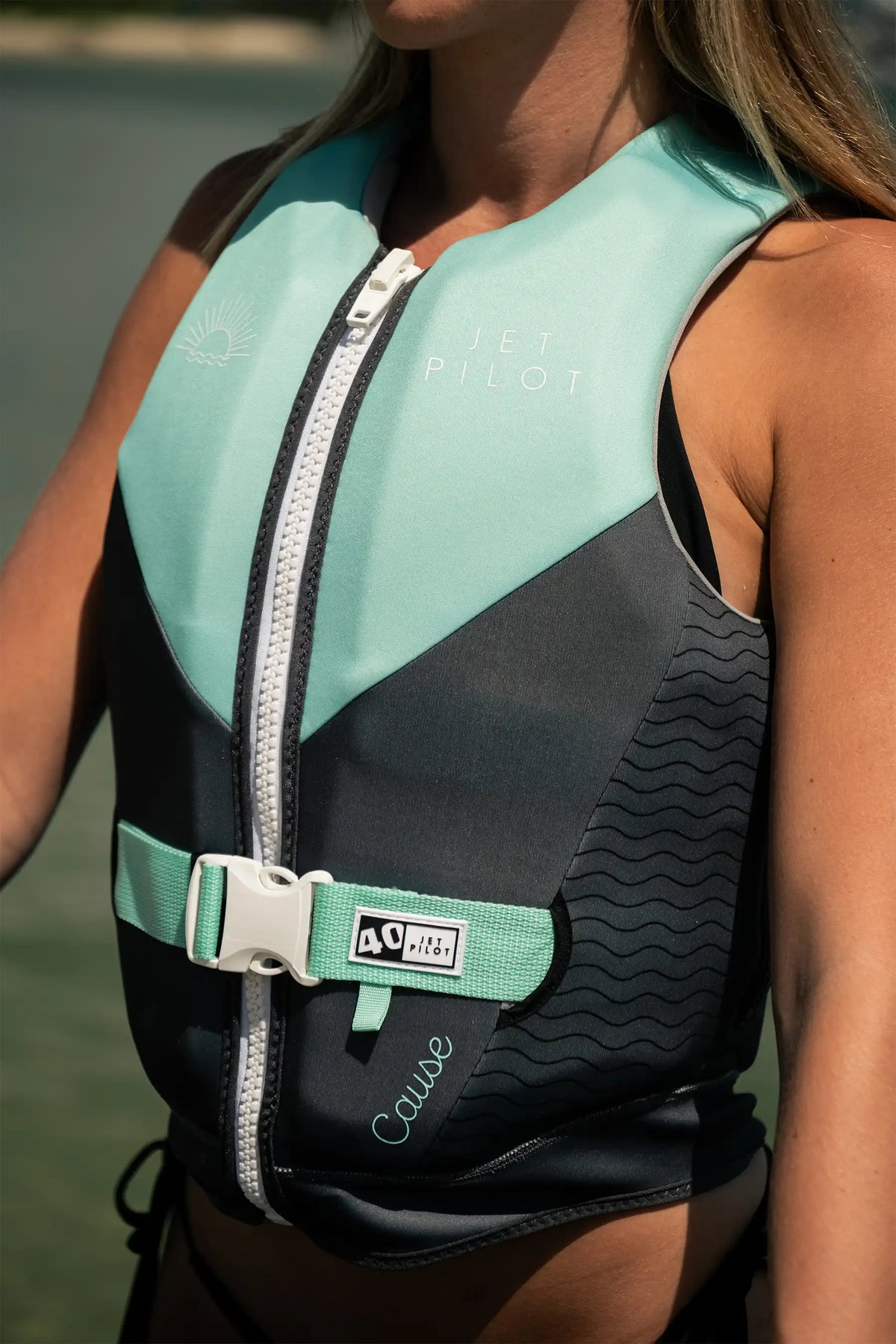 Close-up of the Teal Cause Ladies on a model, showing the white zip, teal waist strap and 40 tab