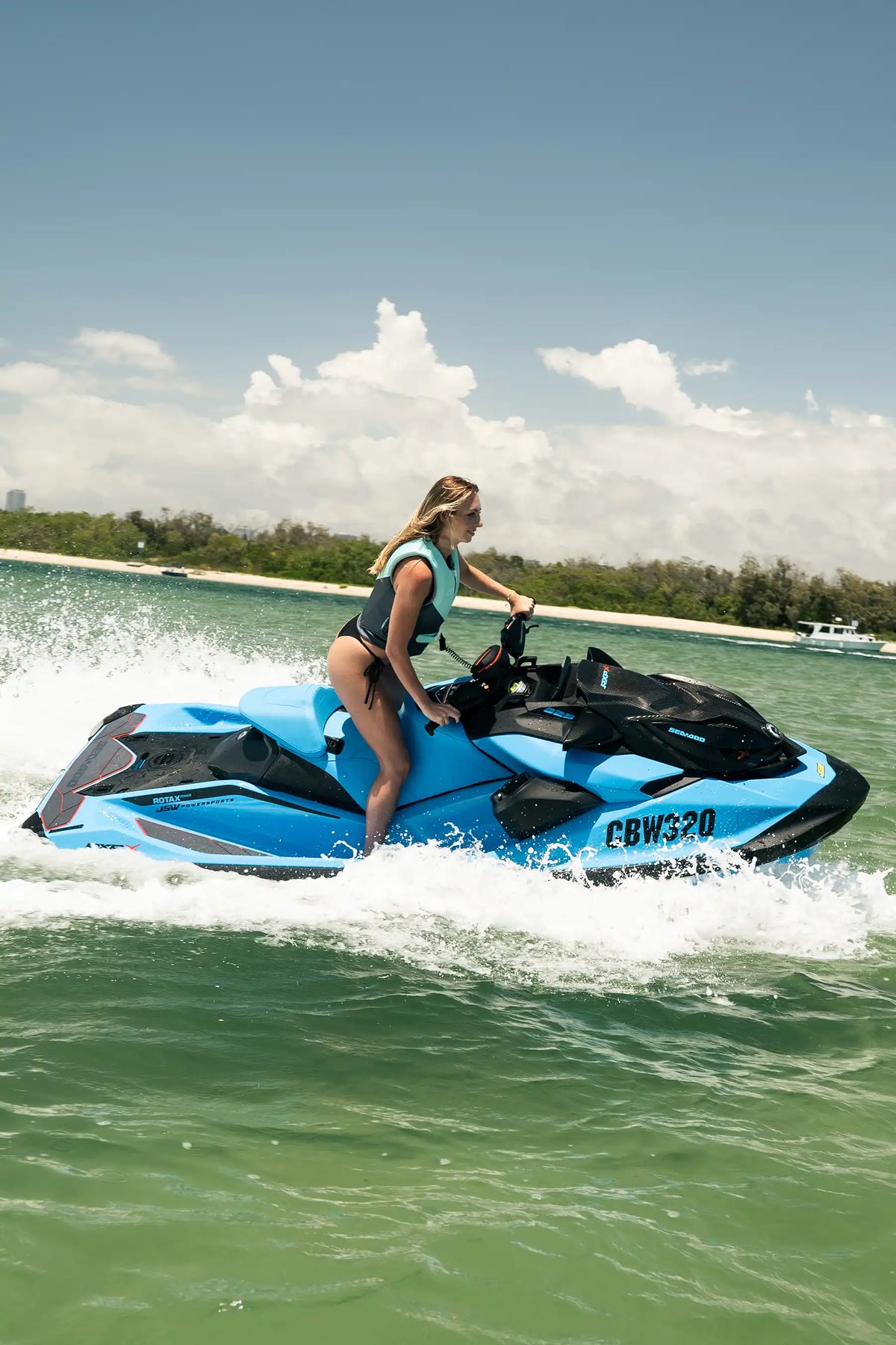 Rider on a jet ski cutting through spray on the water in the Teal Cause Ladies