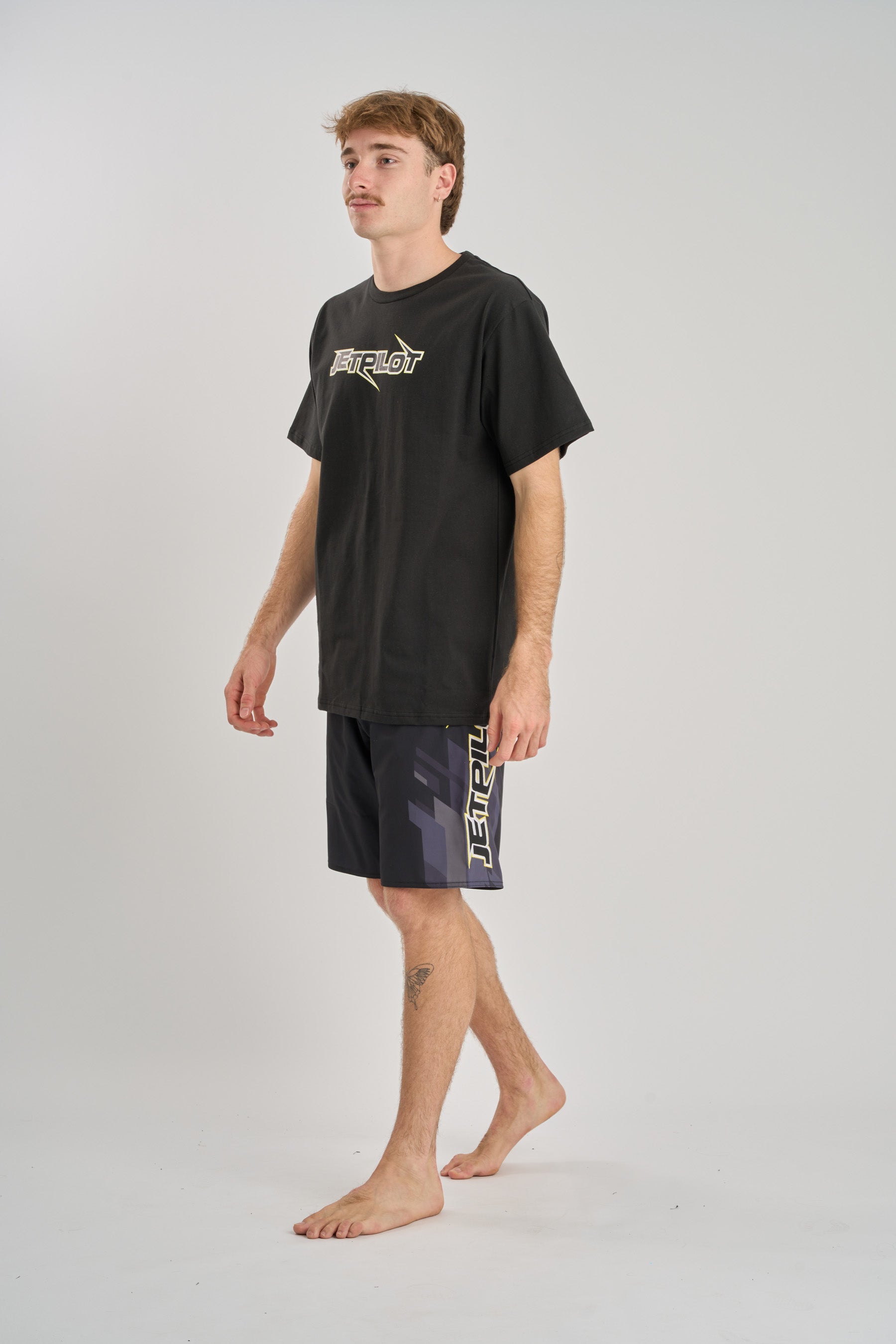 Person wearing a black t-shirt and shorts with a logo on a white background