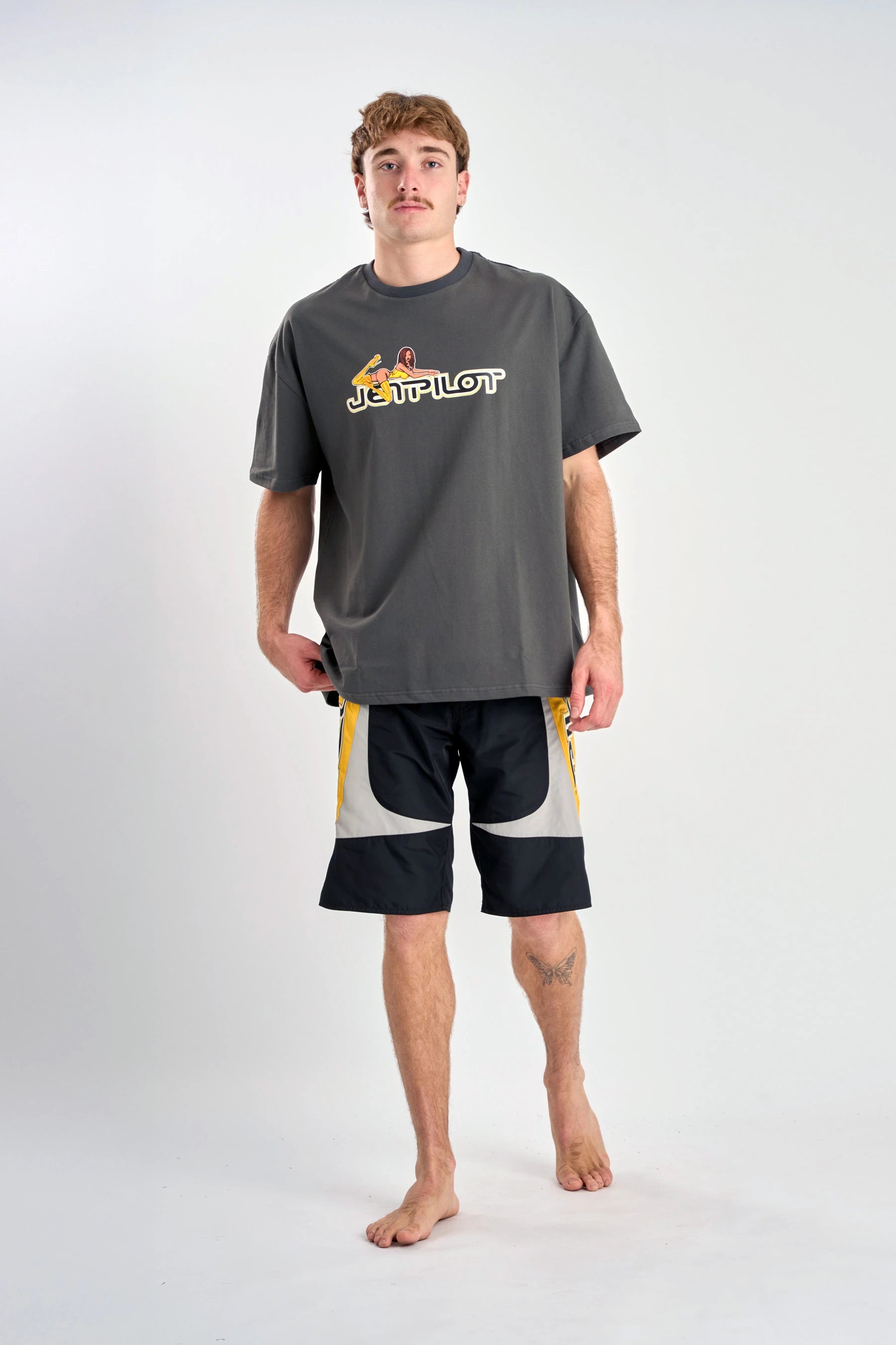 Person wearing a grey t-shirt with a logo and black shorts on a white background