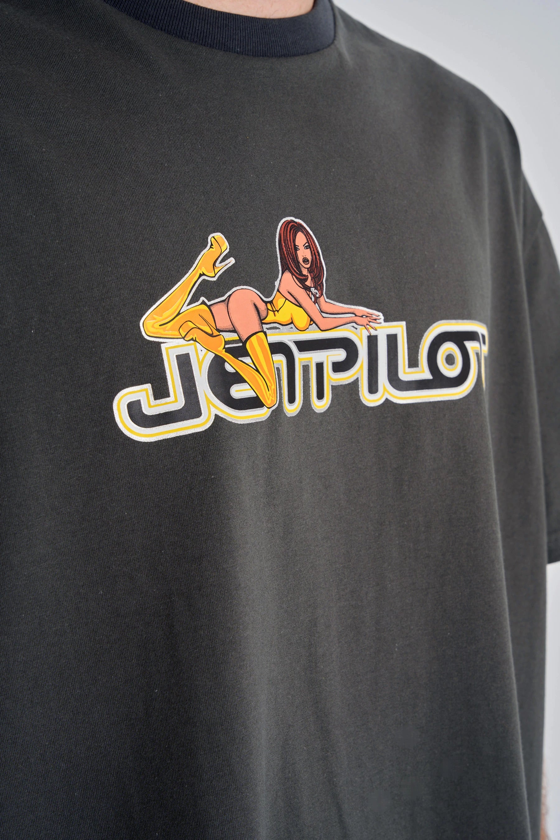 Jetpilot Moto Heavy Tee - Charcoal with a graphic design featuring a woman lying on logo graphic "Jetpilot" on a plain background.