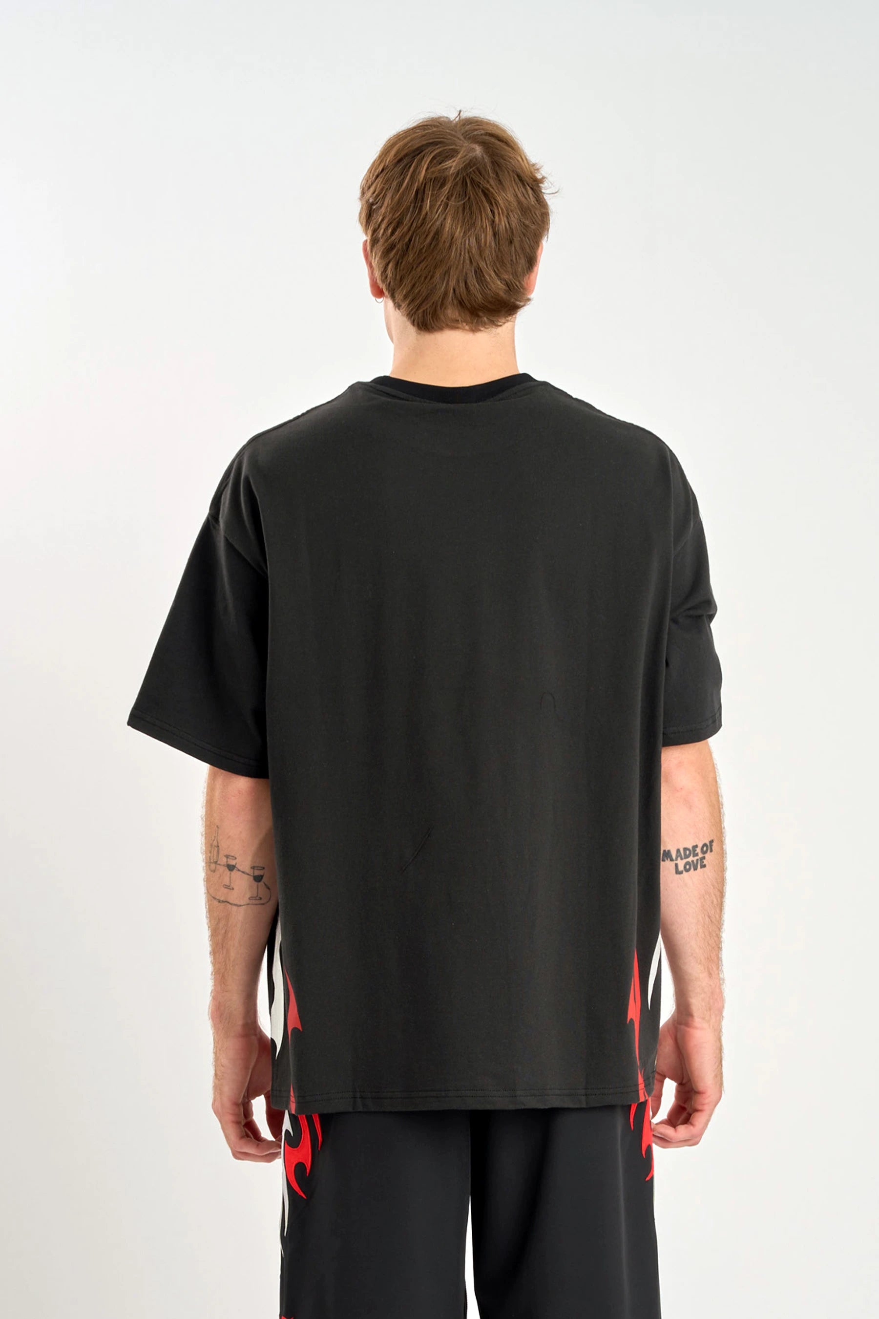 Back view of a person wearing a Jetpilot Tribal Heavy Tee - Black with red/grey accents around the bottom of the shirt on a w