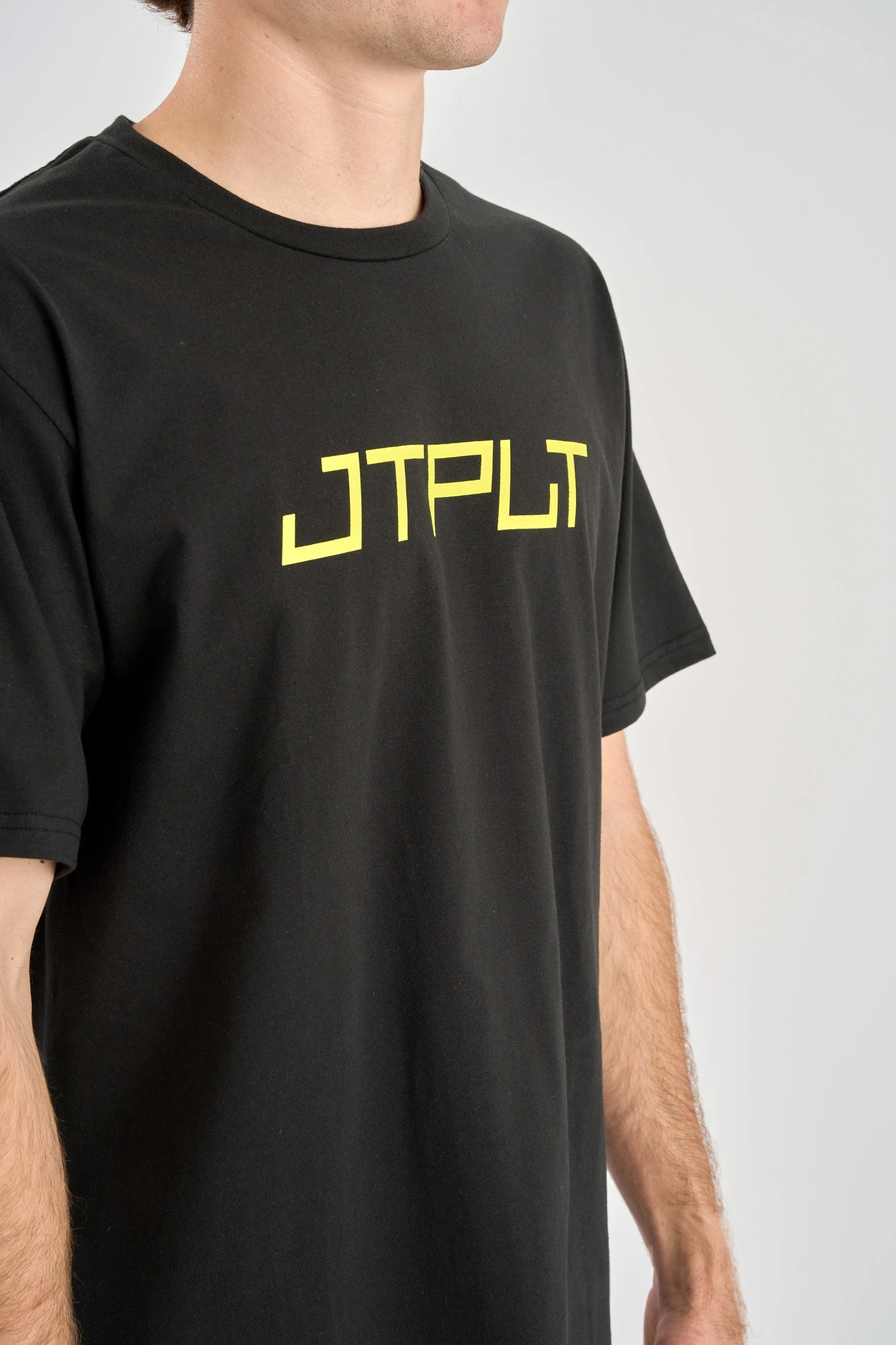 Person wearing a black t-shirt with yellow text on a plain background — image 2