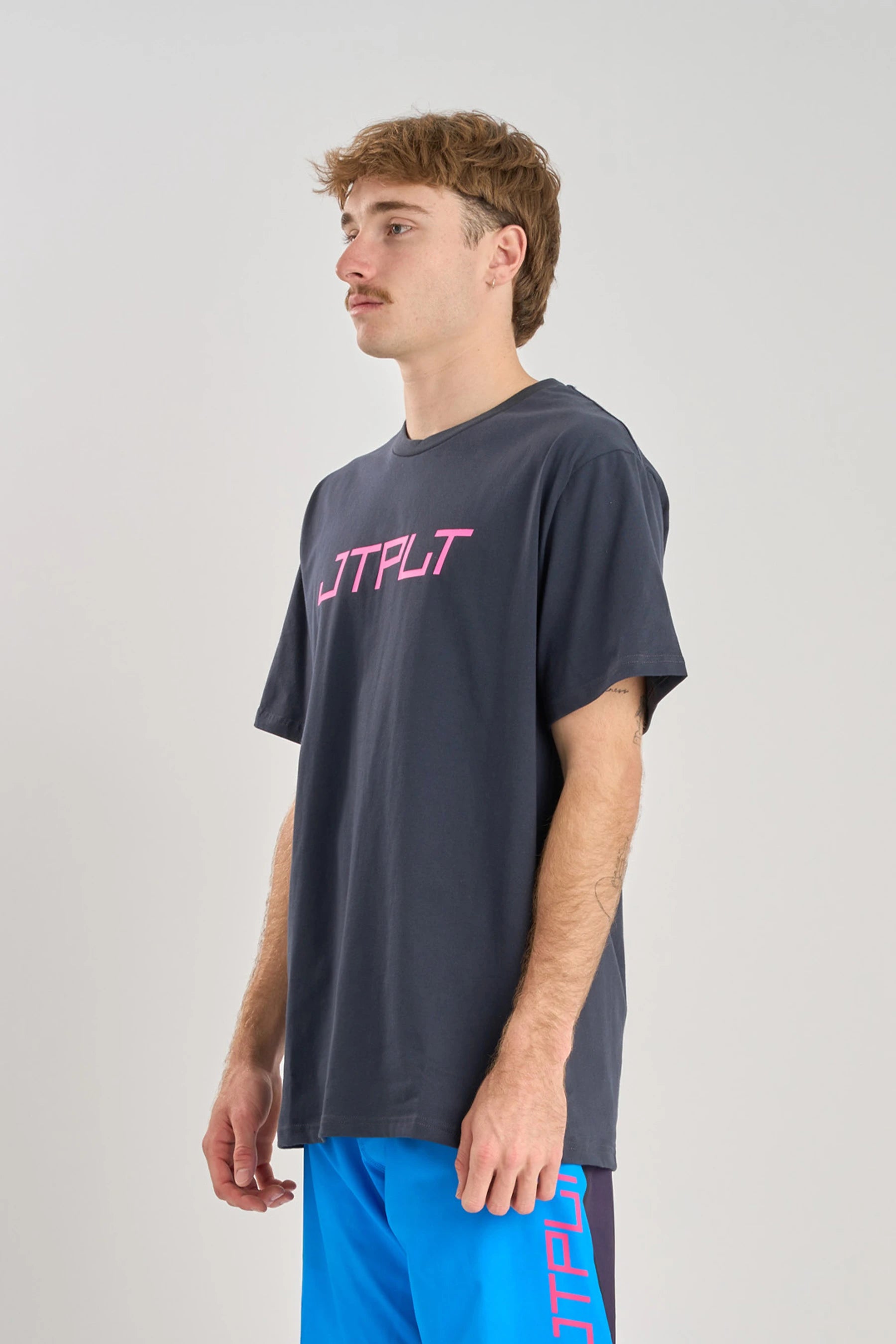 Person wearing a Jetpilot Vault SS Tee - Navy with pink text on a light gray background — image 2