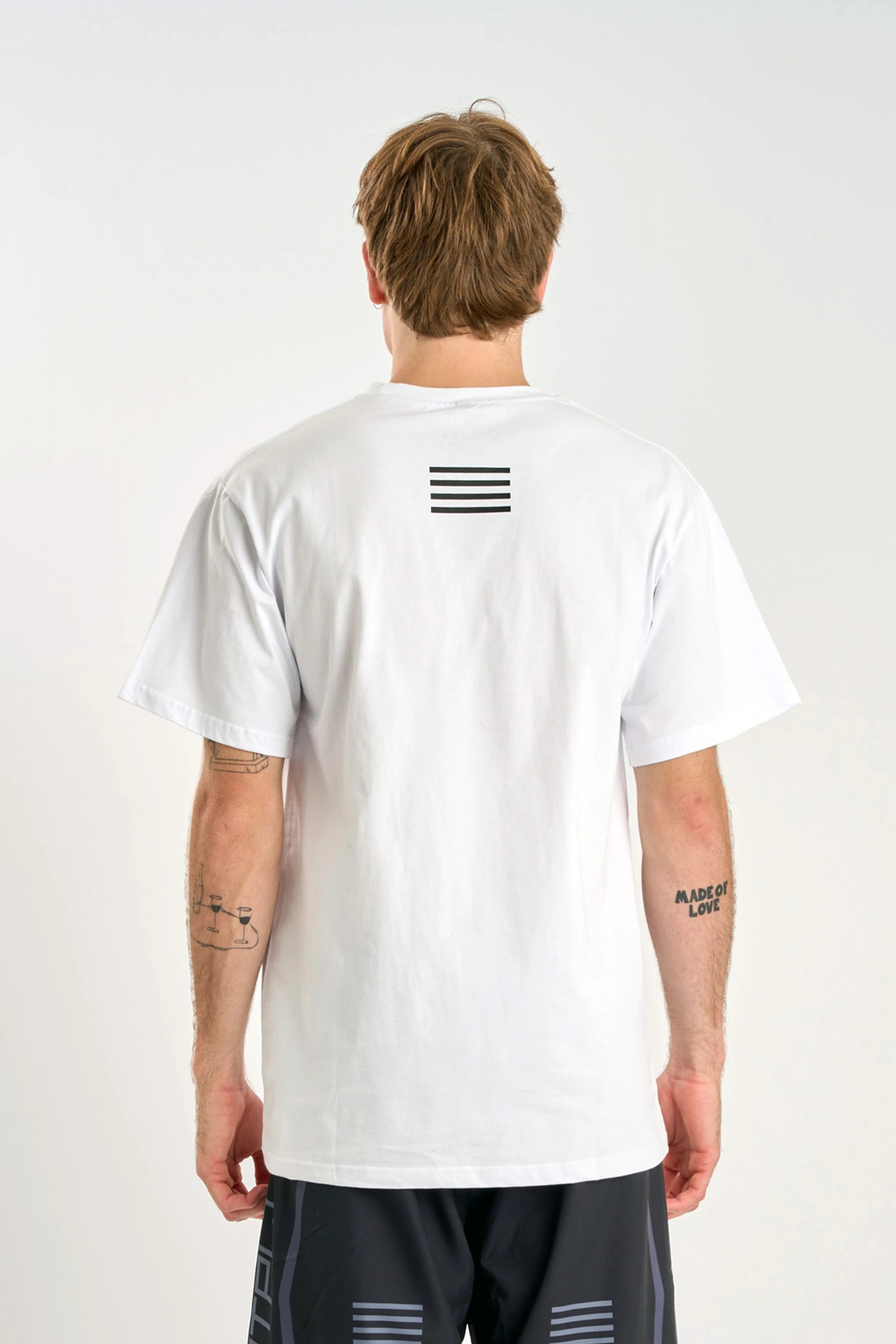 Person wearing a Jetpilot Vault SS Tee - White t-shirt with a black logo on the back against a white background — image 2
