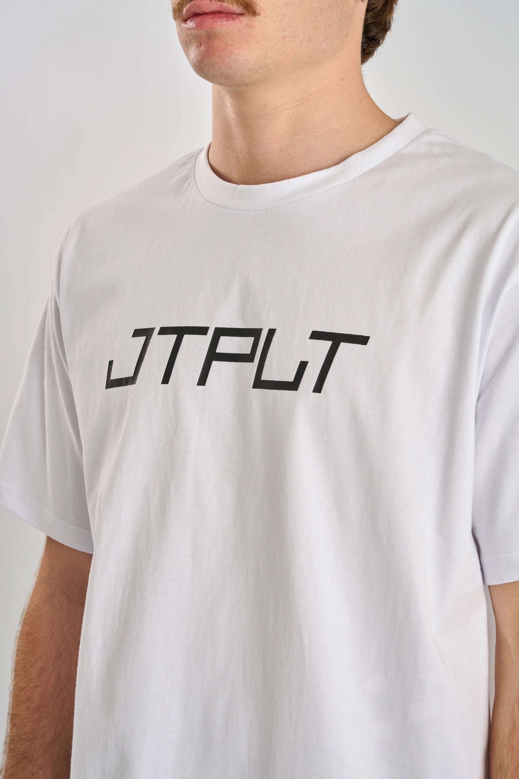 Person wearing a Jetpilot Vault SS Tee - White t-shirt with 'JTPLT' logo on a plain background — image 2
