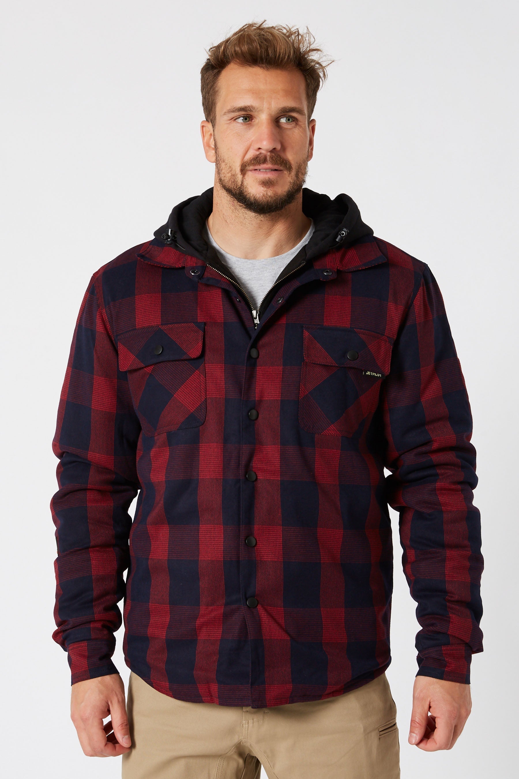 Man wearing Jetpilot quilted flannel jacket in red and navy check with black hood — warm insulated winter flanno Australia