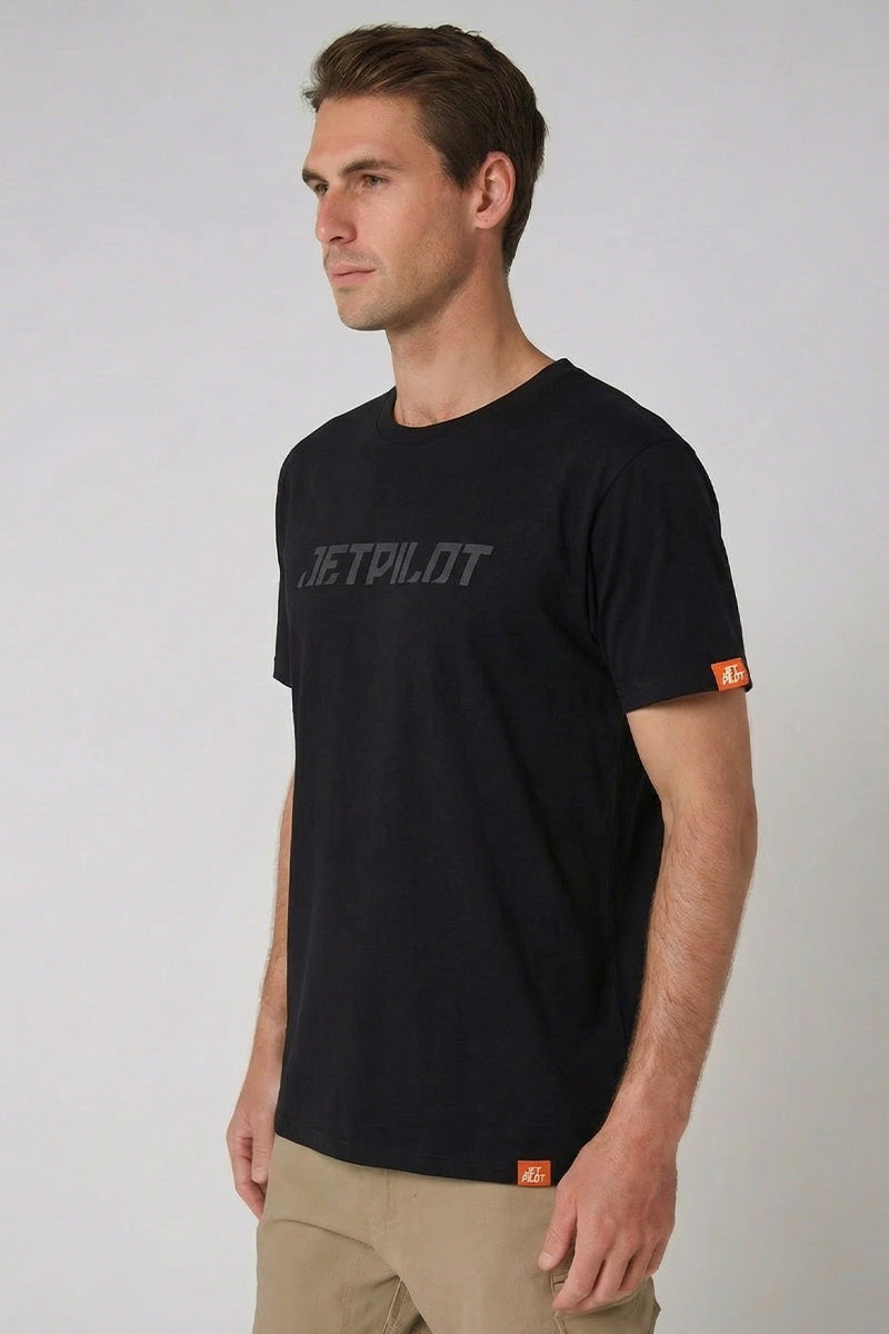 Man wearing a black t-shirt with a brand logo on a light gray background — view 2 (3)