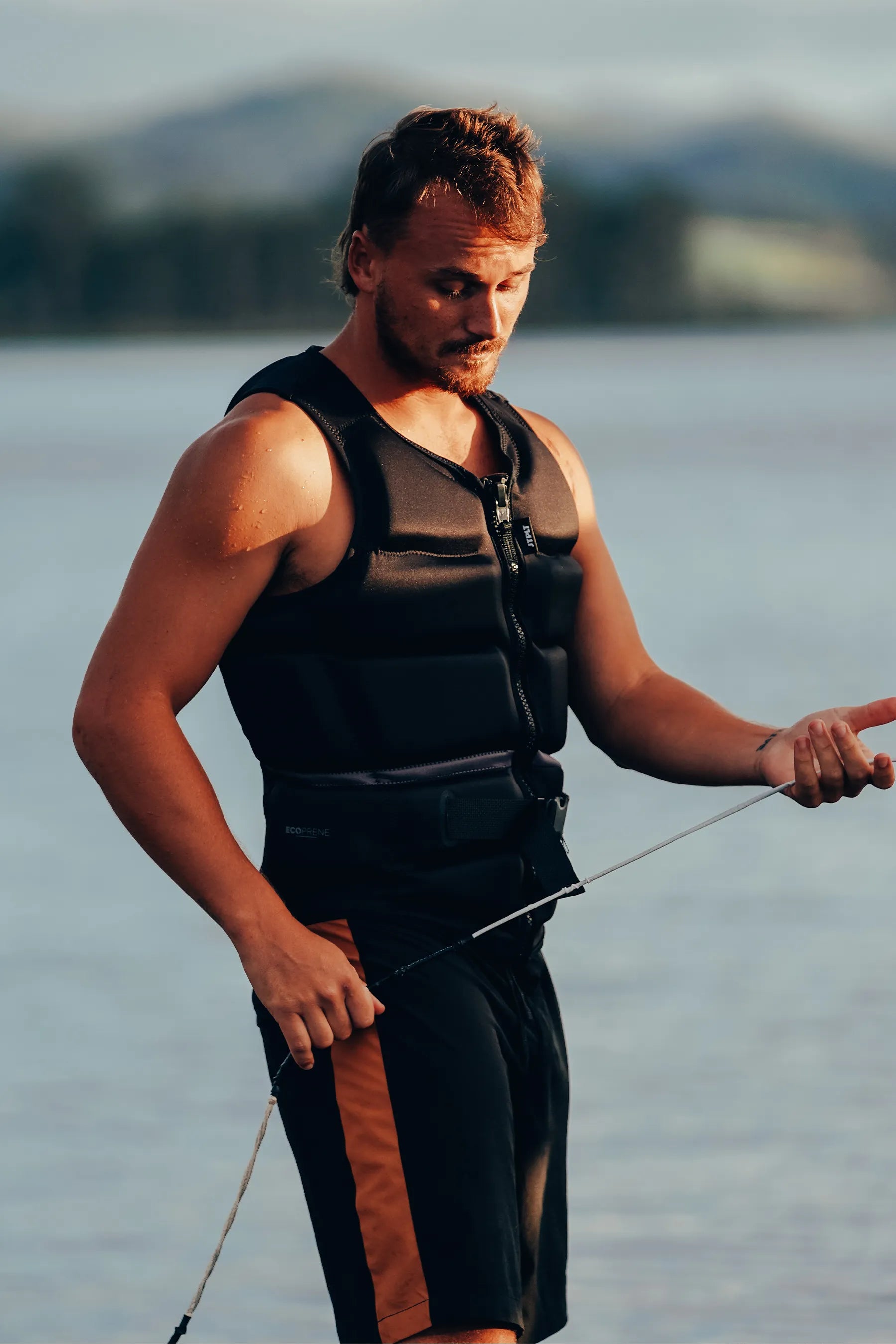 Man wearing aJetpilot C4 Mens Life Jacket - Cory Tuenissen Signature Series - Black on a body of water