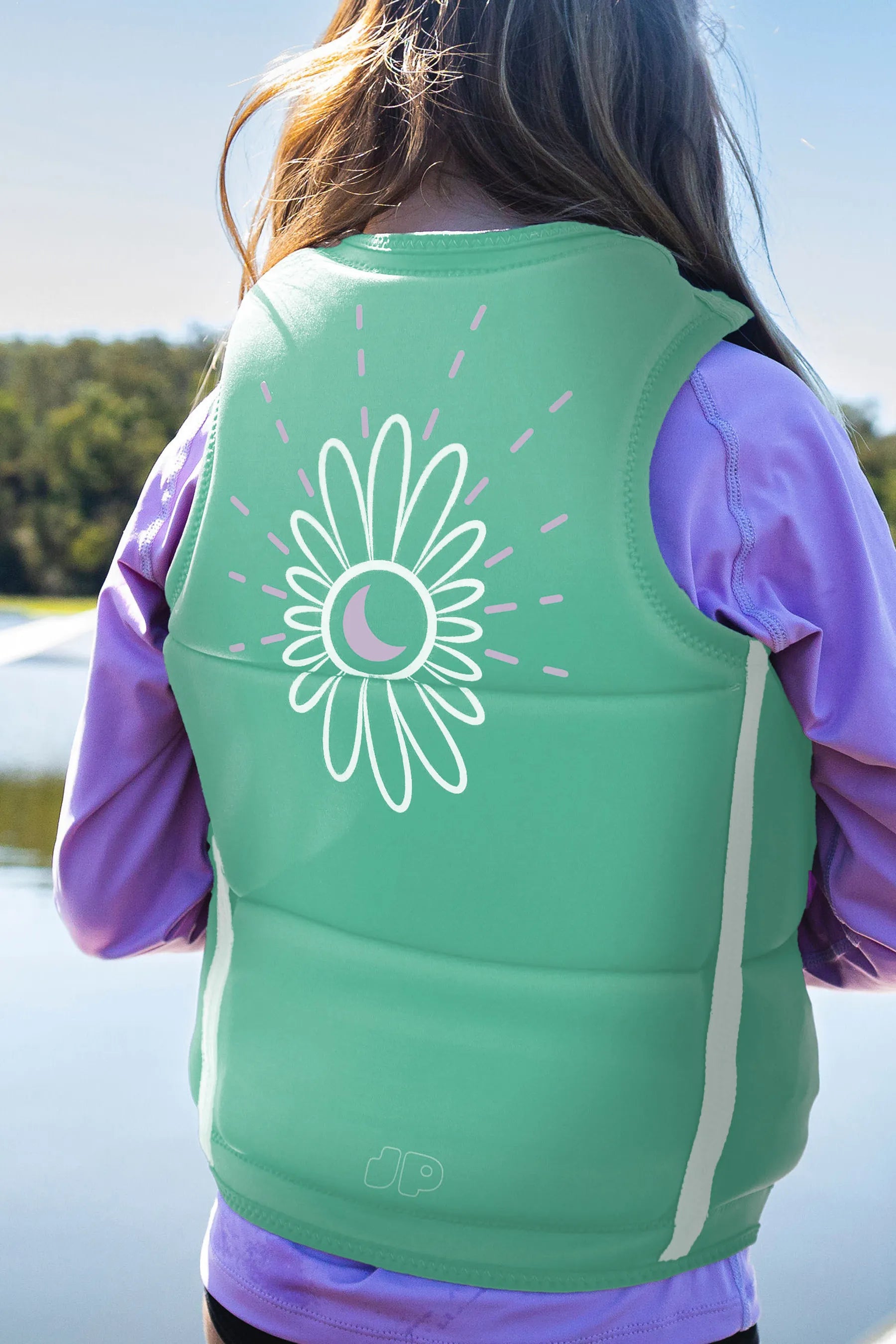 Child wearing a Jetpilot Freeride Girls Life Jacket - Teal with a white floral design outdoors