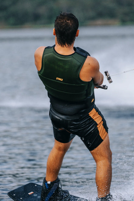 Person water skiing wearing a Jetpilot Pro C4 Life Jacket - Cory Tuenissen Signature Series - Black/Sage and black shorts on a lake.