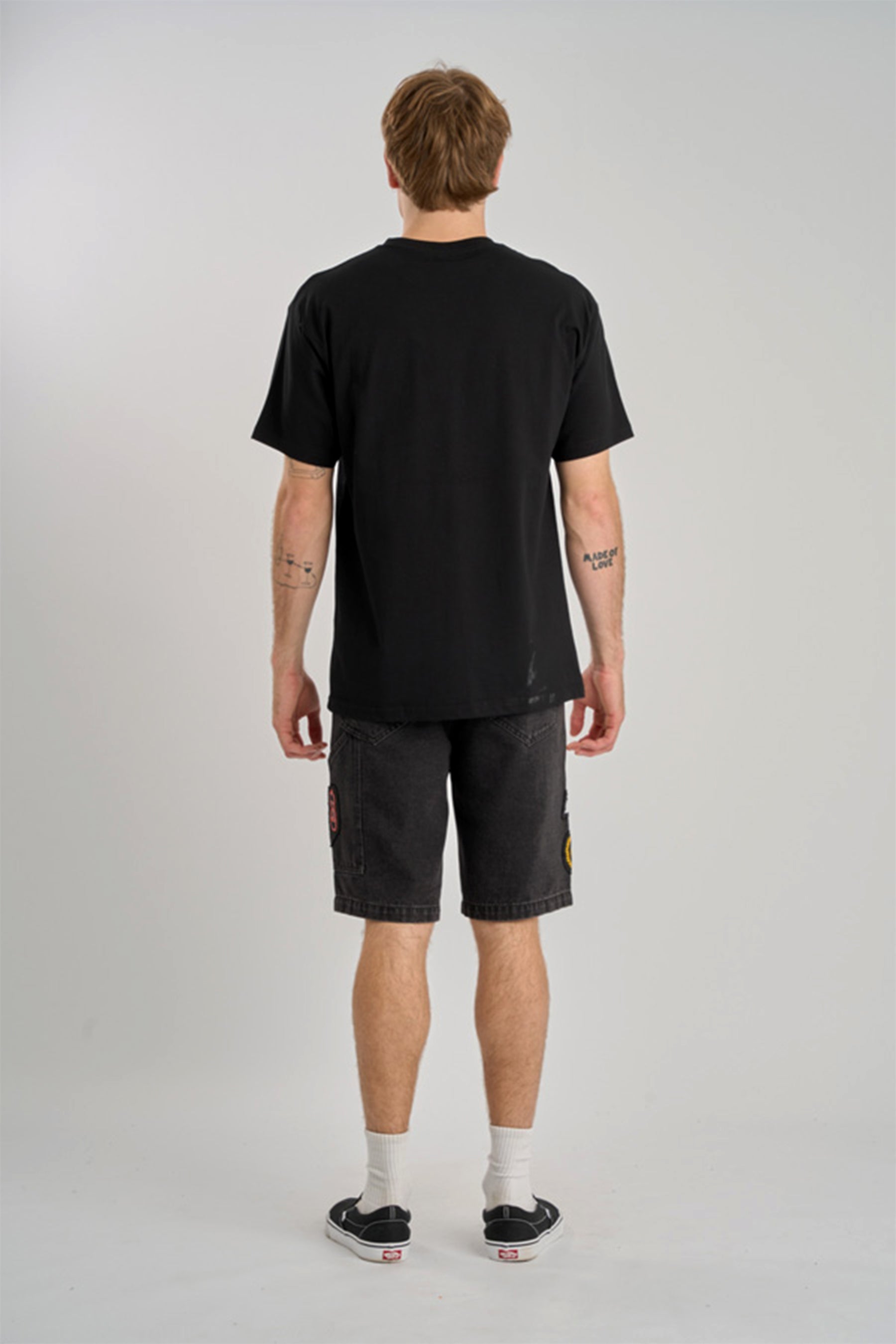Person wearing a black t-shirt and dark shorts on a plain background
