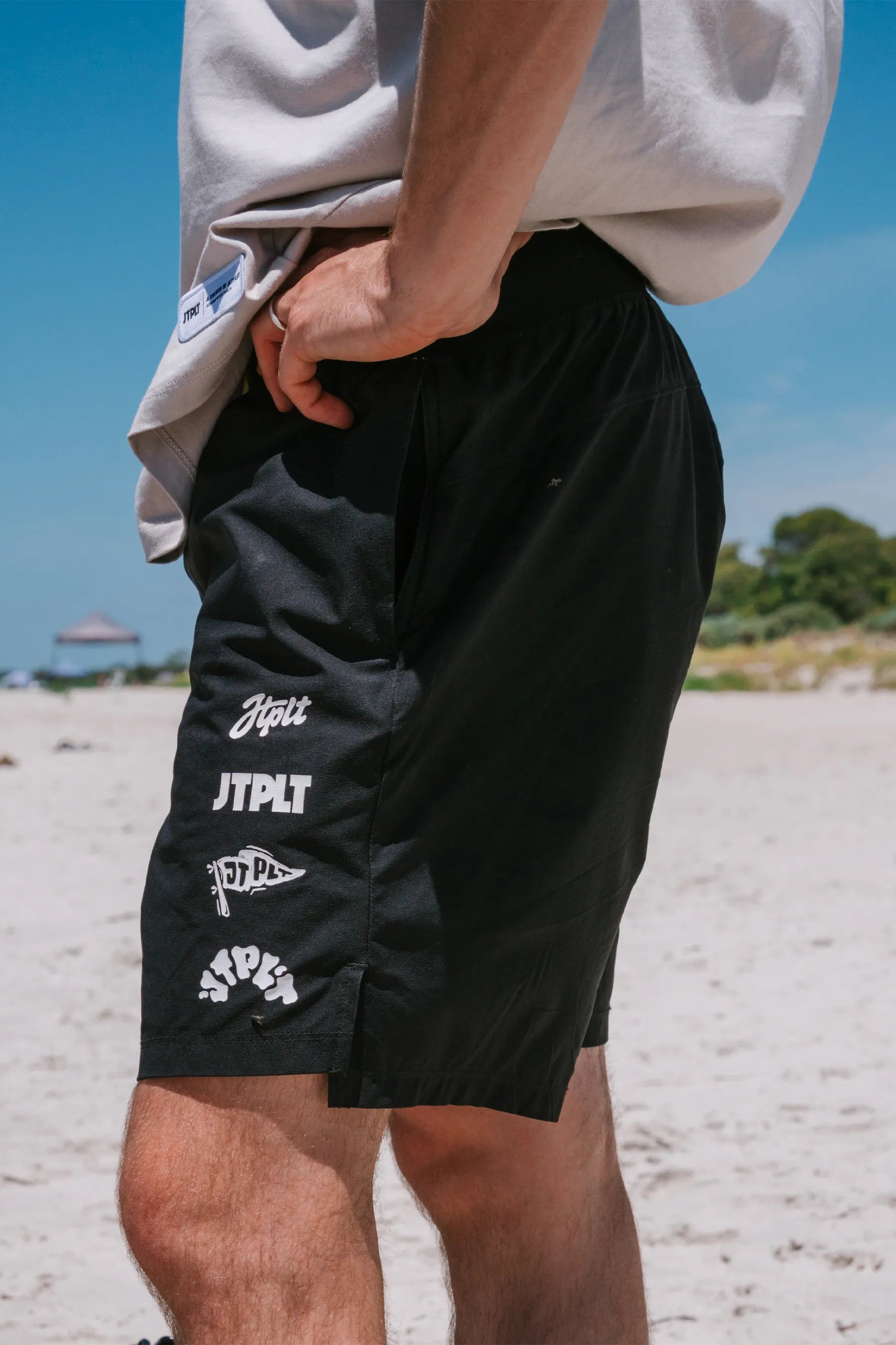 Person wearing Jetpilot Superfan Boardshorts - Blacks with white branding on a beach.