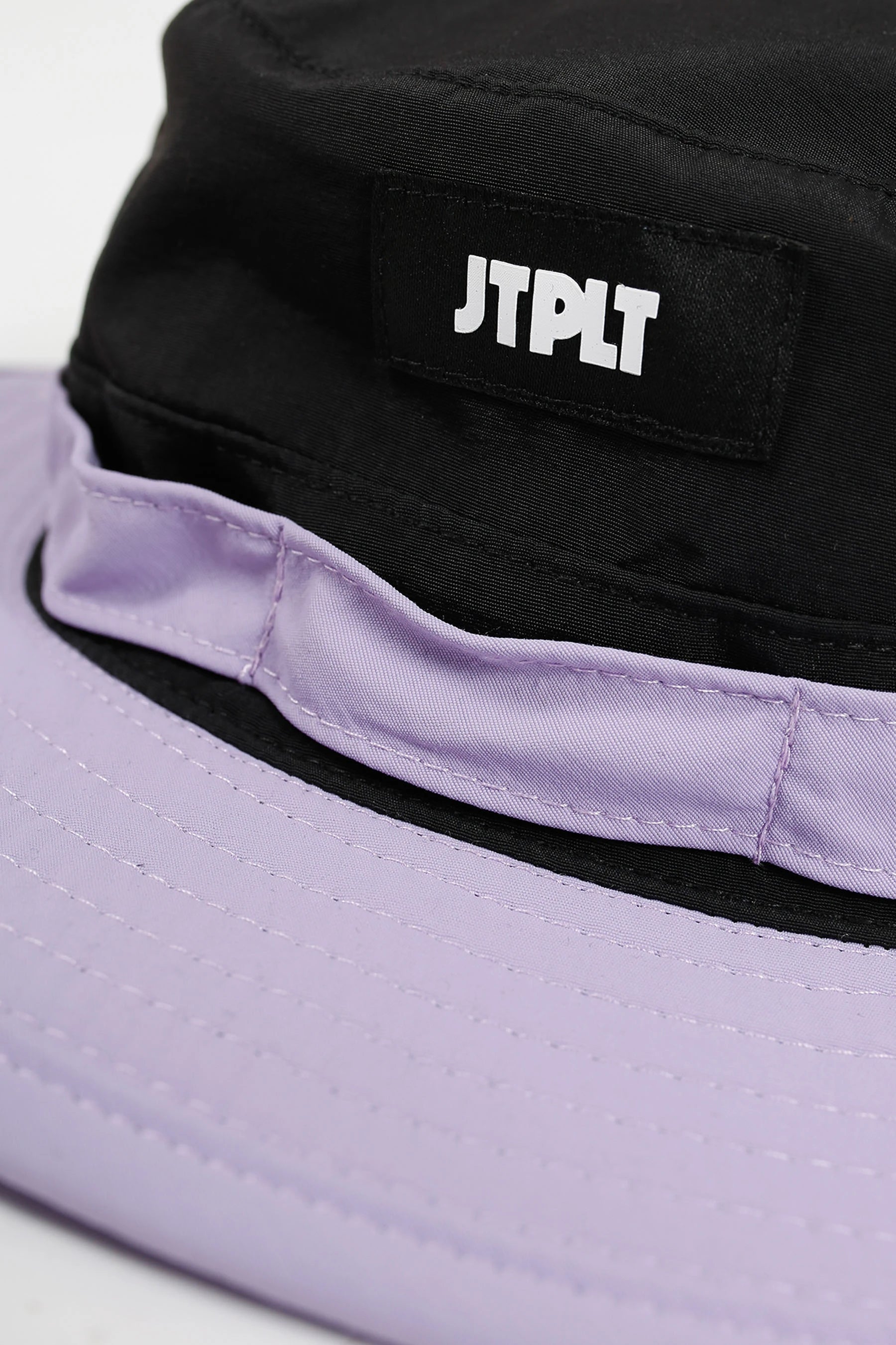 Black and purple bucket hat with 'JTPLT' logo on a white background
