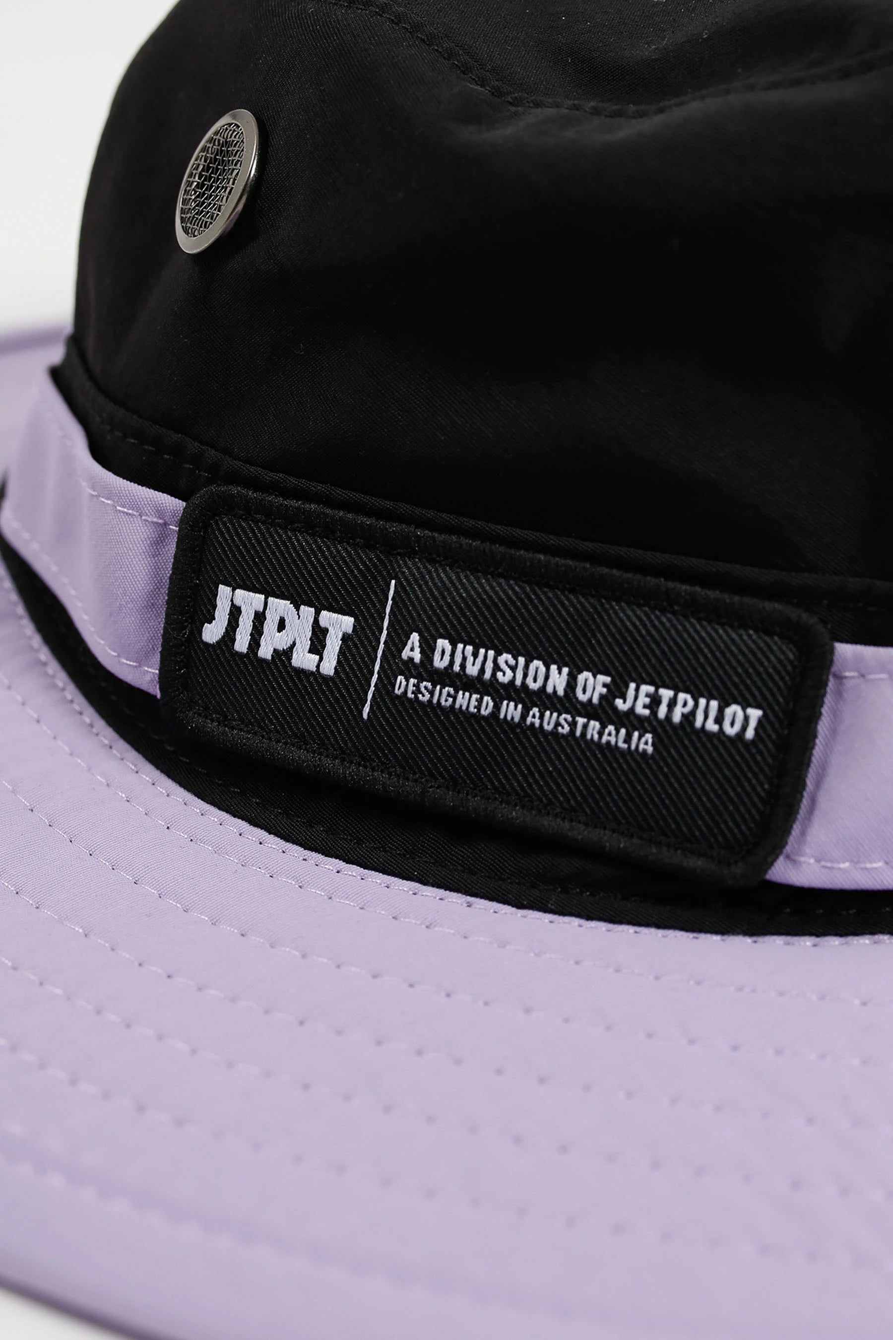 Close-up of a black and purple cap with a brand logo on a white background