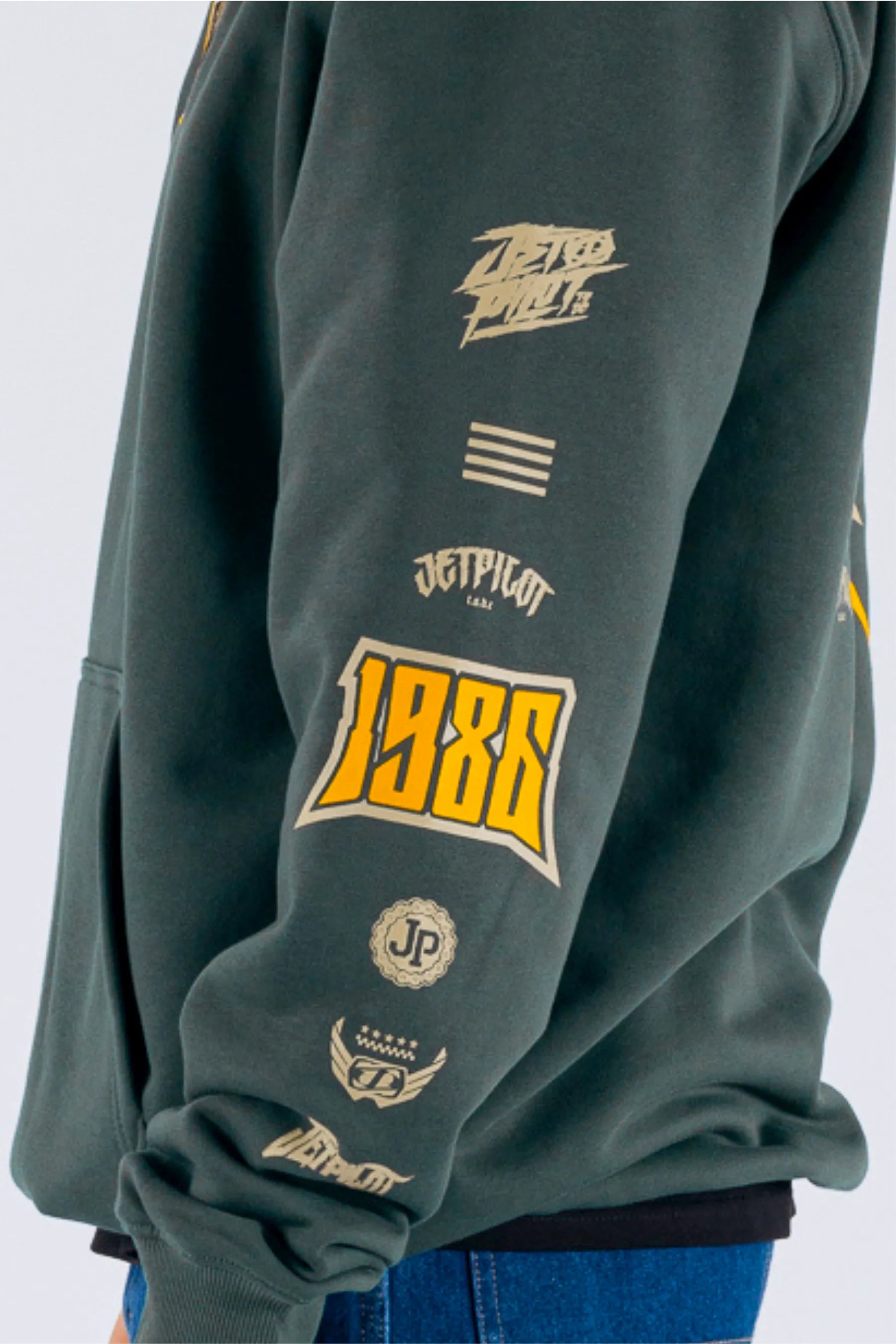 side view of a person wearing an amazon green pullover with a Jetpilot logos on a white background — view 3 (3)