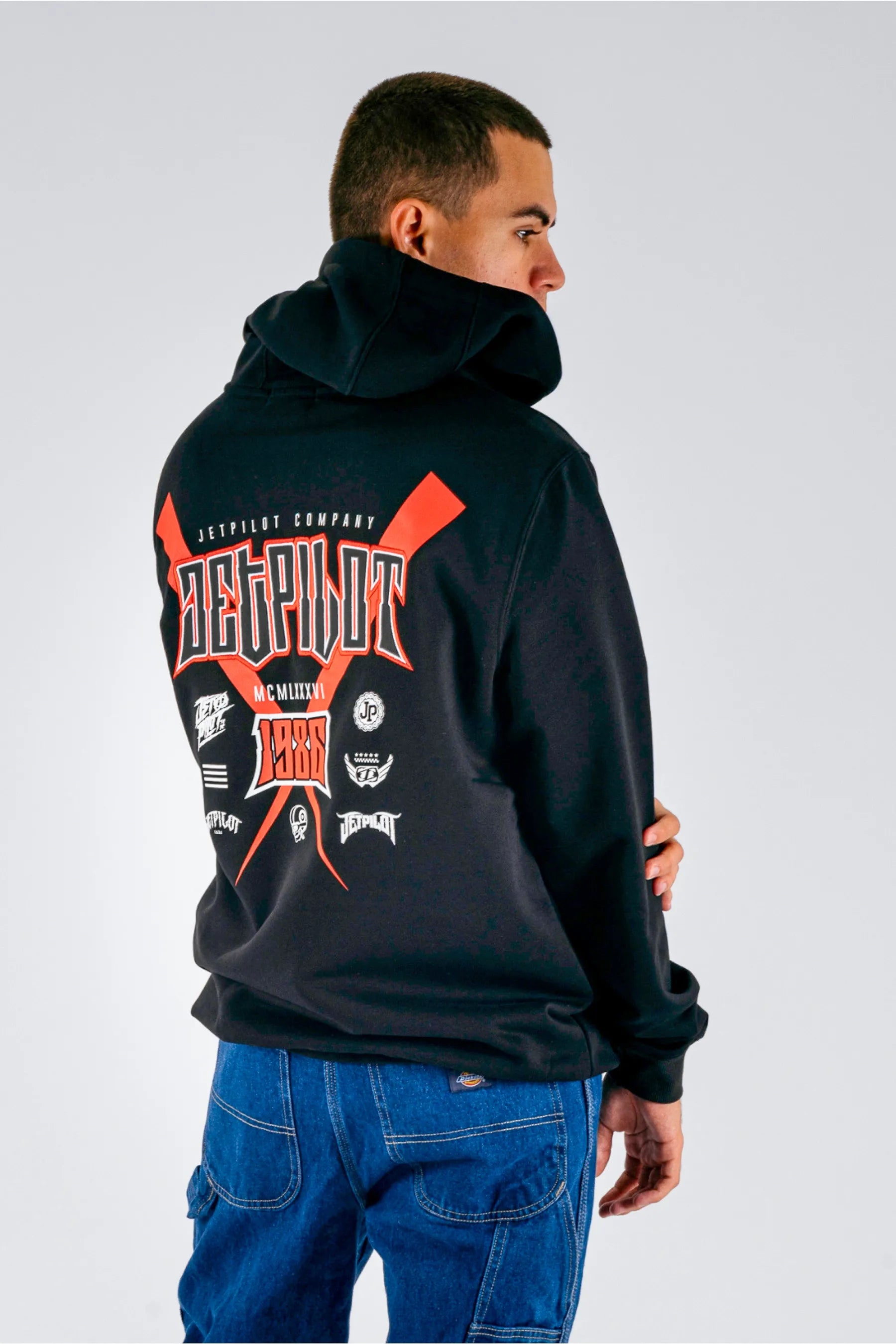 back view of a person wearing a black pullover with a Jetpilot logos and graphics on a white background — view 3 (3)