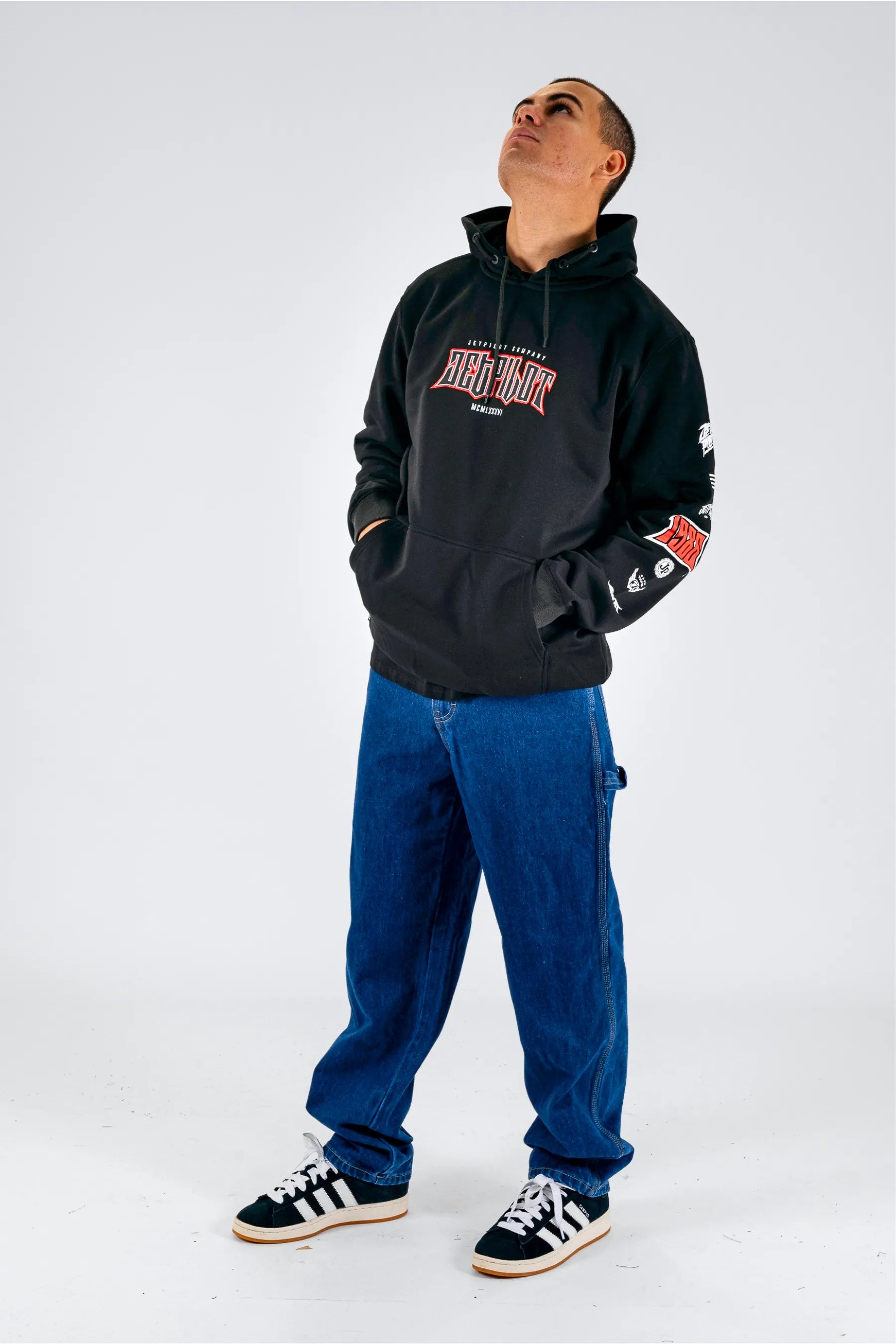 a person wearing a black pullover with a Jetpilot logo, blue shorts and a black/white shoes — view 5 (8)