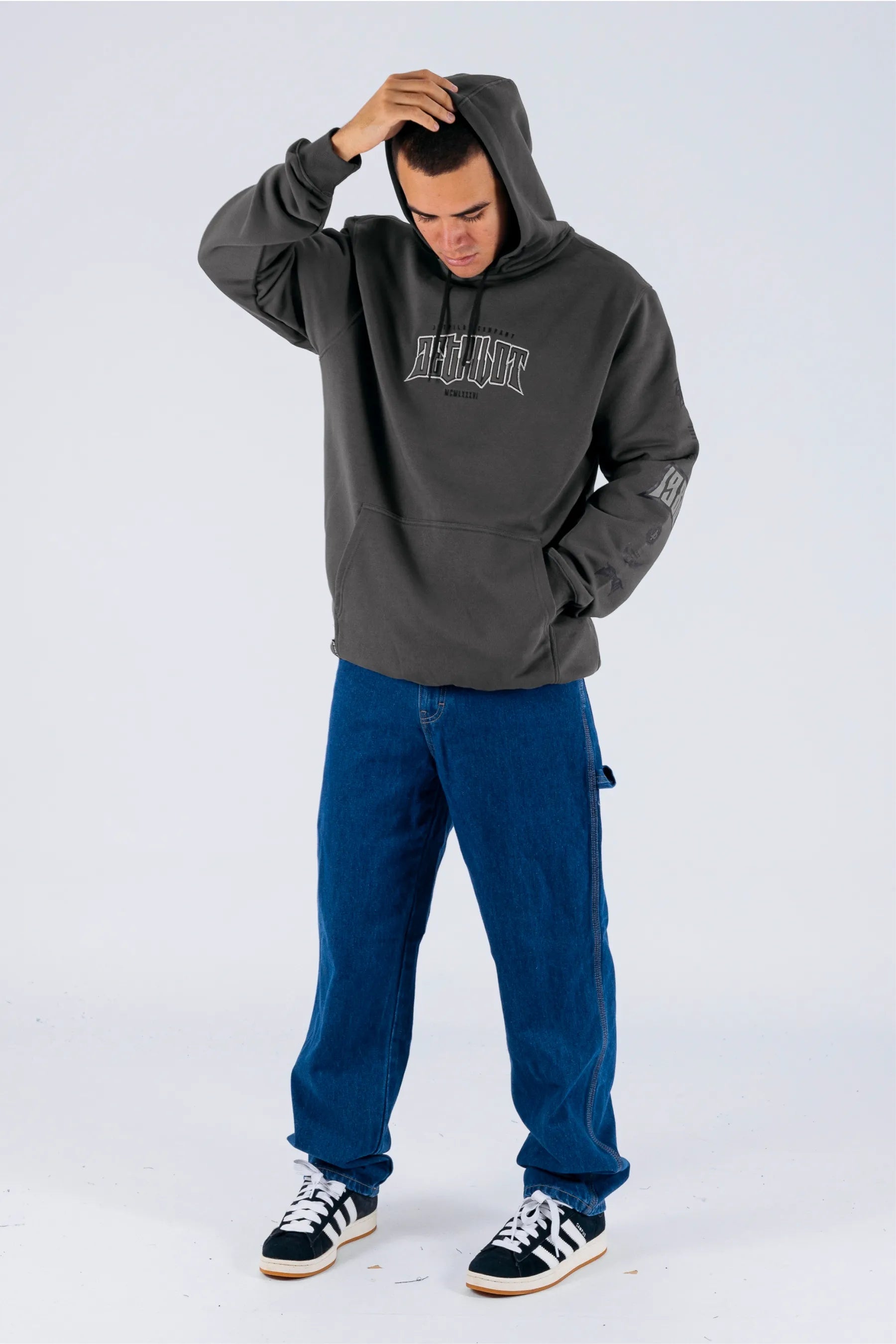 a person wearing a charcoal pullover with a Jetpilot logo, blue shorts and a black/white shoes — view 3 (5)