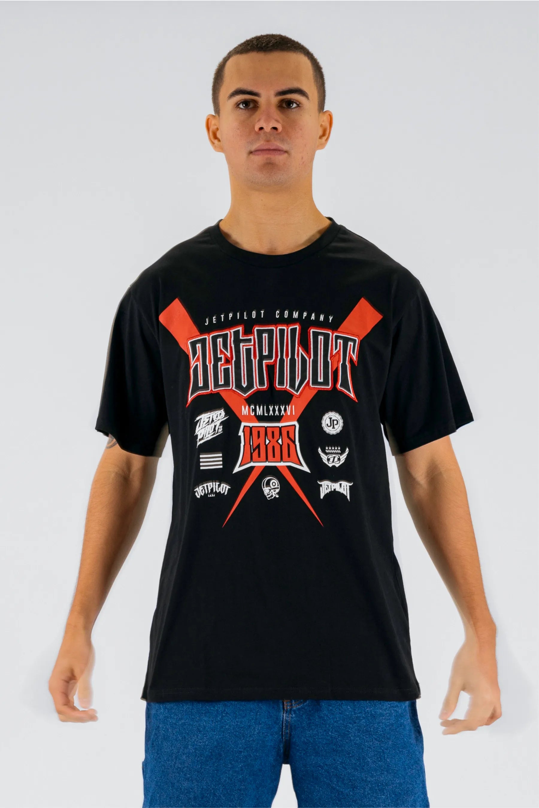 Front view of a person wearing a black tee with Jetpilot logos on a white background — view 1 (3)