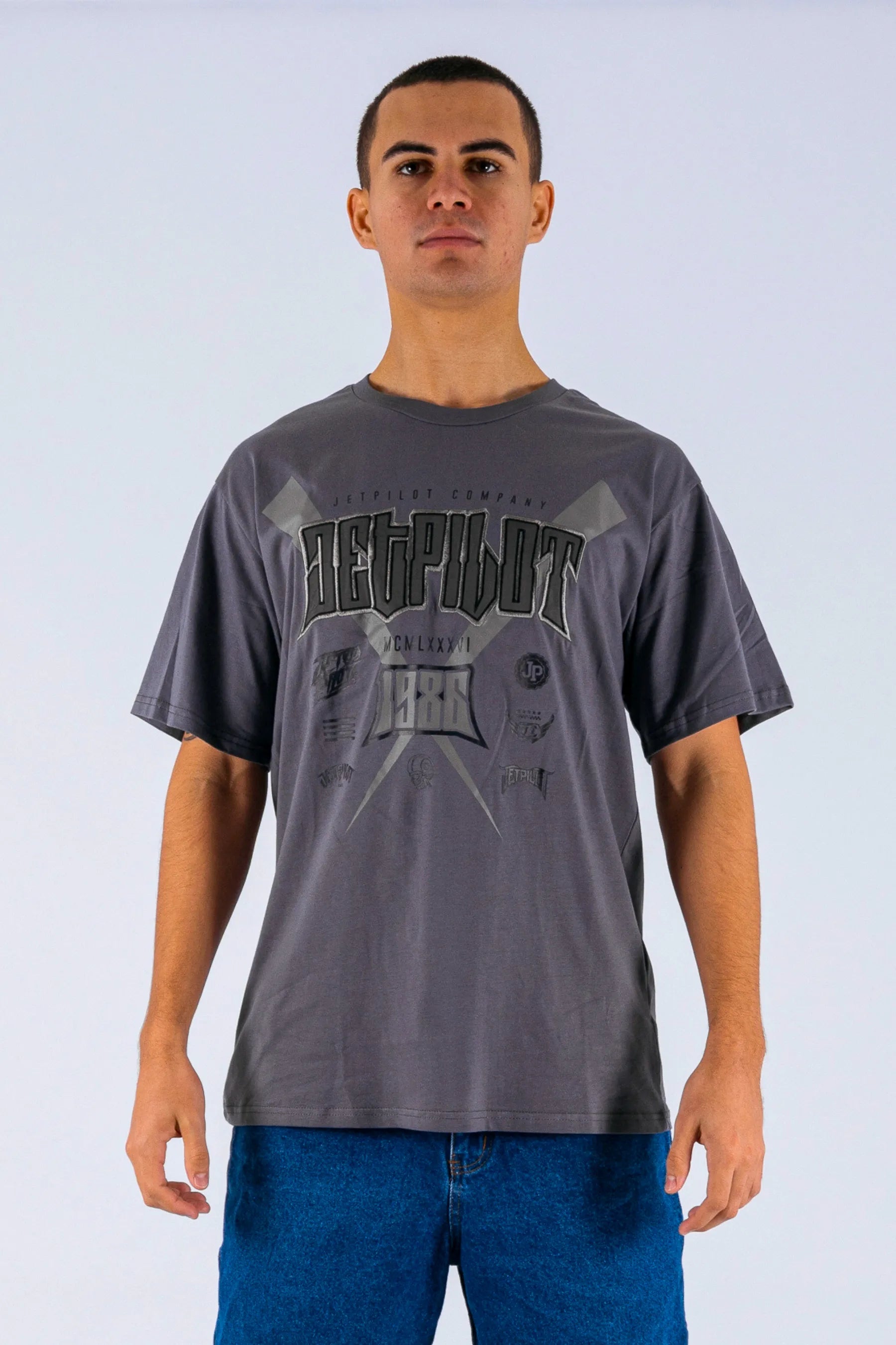 Front view of a person wearing a charcoal tee with a Jetpilot logo on a white background — view 1 (3)