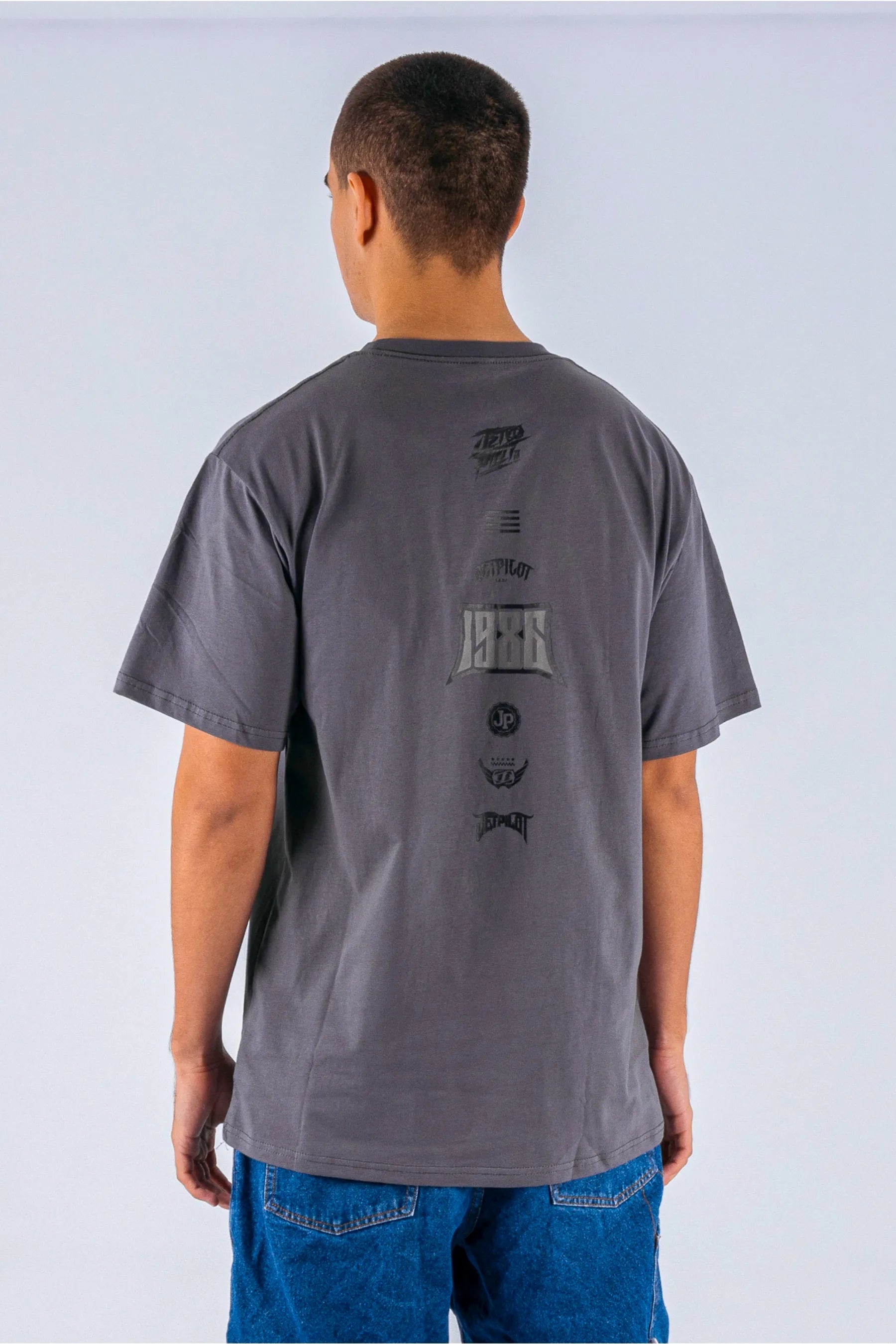 Back view of a person wearing a charcoal tee with a Jetpilot logos on a white background — view 2 (3)