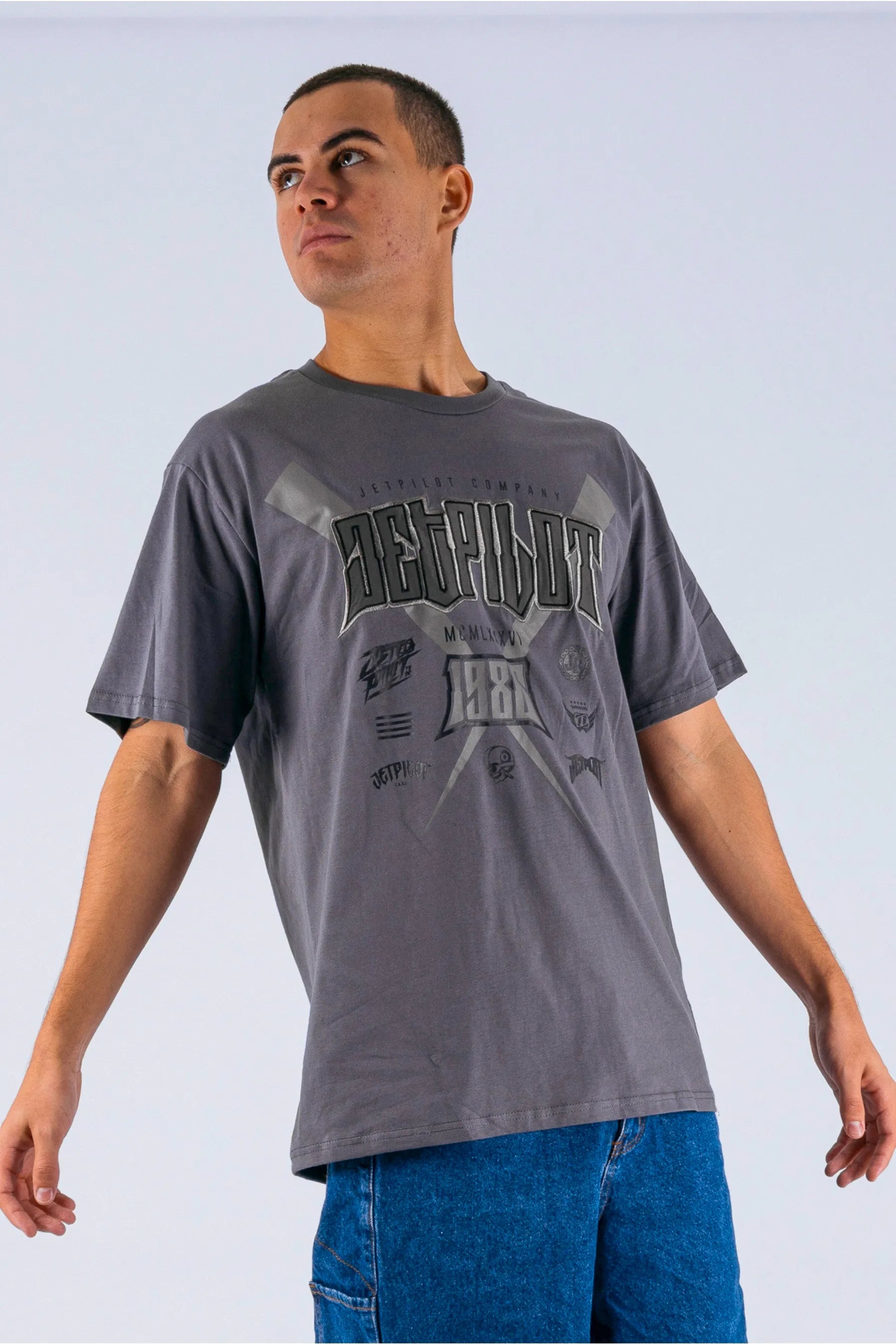 Angled view of a person wearing a charcoal tee with a Jetpilot logo on a white background — view 4 (3)