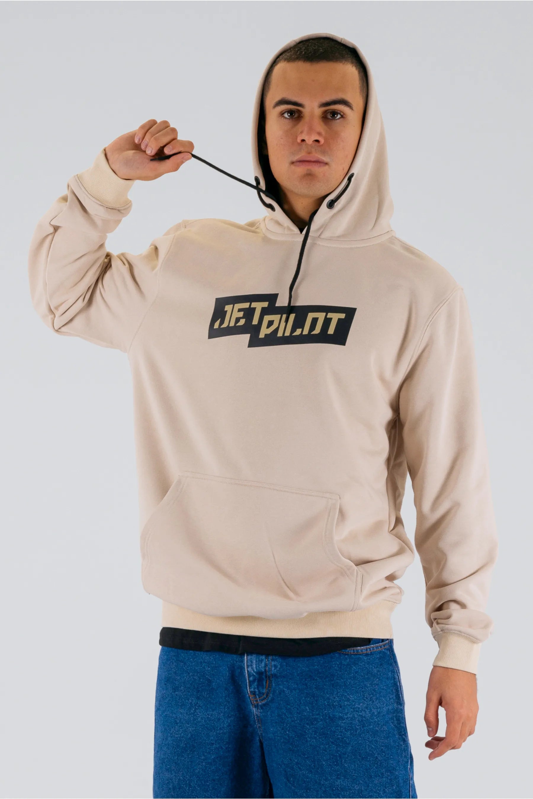 Front view of a person pulling the hood strings of a cement pullover with a Jetpilot logo on a white background — view 3 (3)