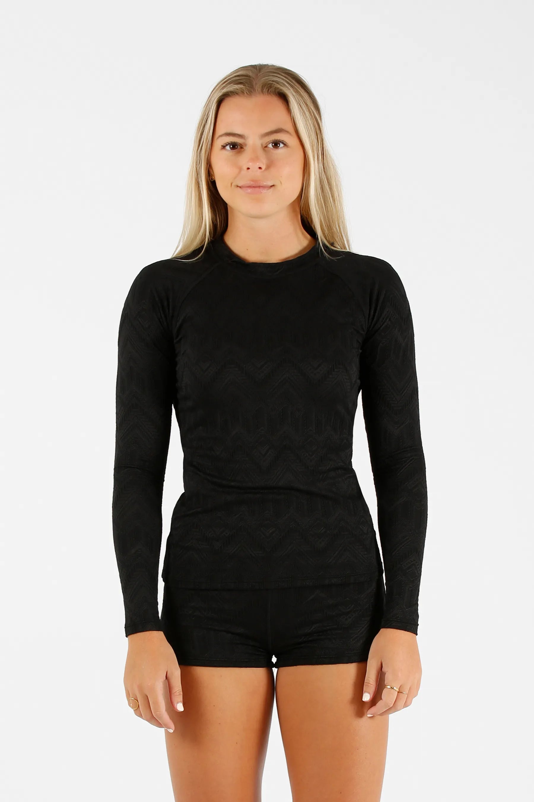Woman wearing a black long-sleeve top and shorts on a white background