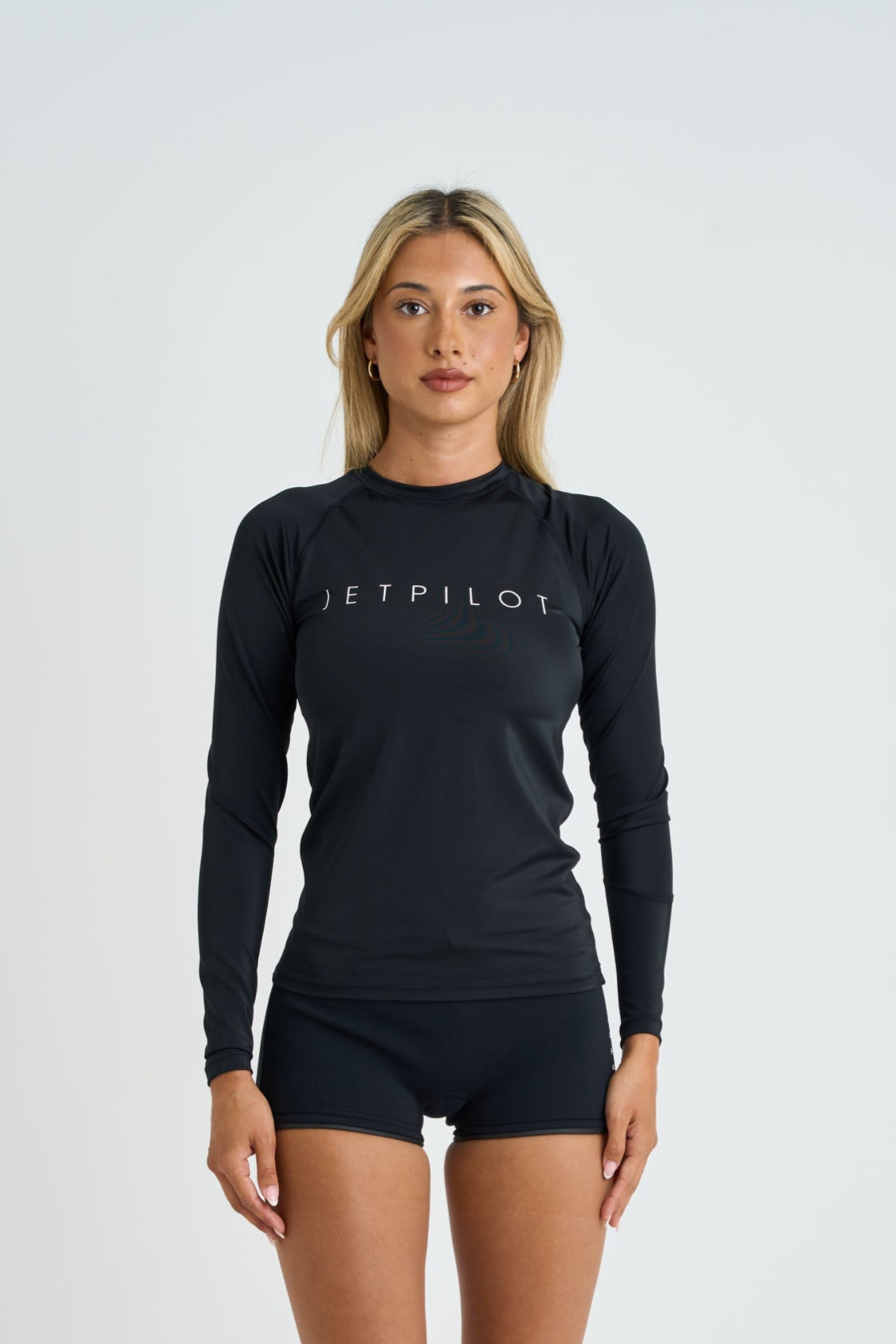 Woman wearing a black long-sleeve top and shorts with 'JETPILOT' branding on a white background — image 2
