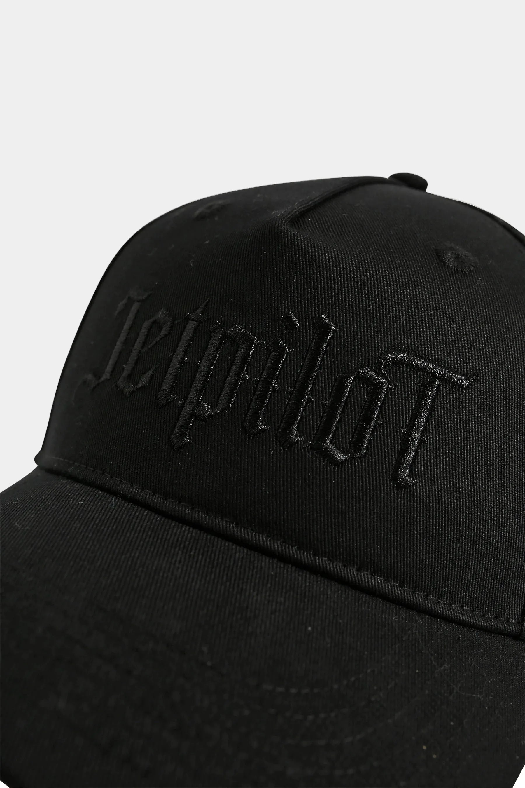 Black cap with 'Jetpilot' embroidered logo on a light grey background