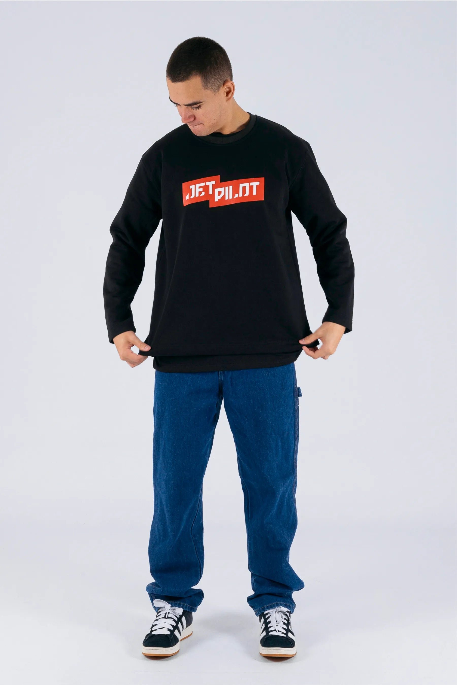 Front view of a person grabbing the sides of the black crew with a red Jetpilot logo on a white background. — view 3 (3)