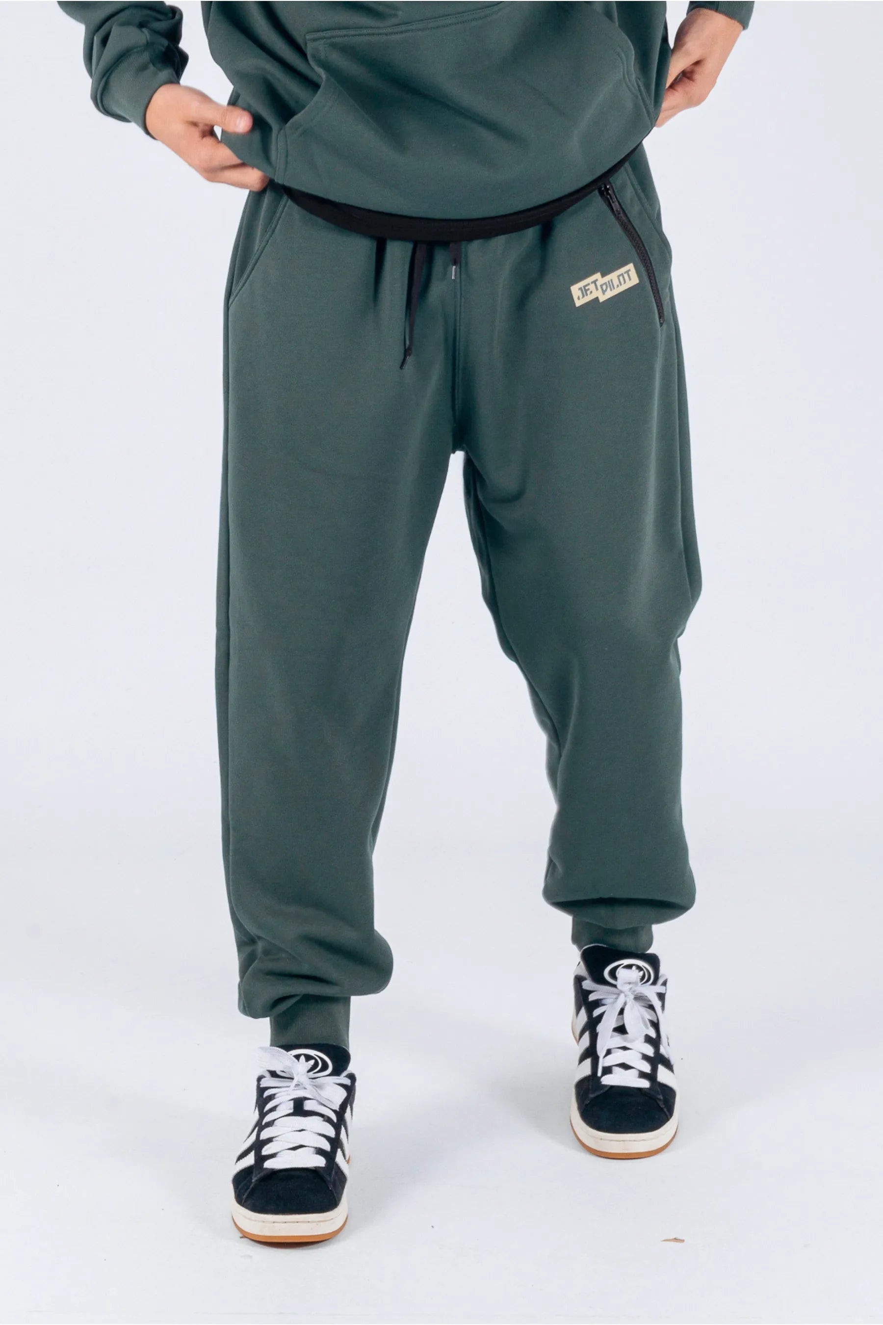 Front view of a person wearing amazon green trackpants with a Jetpilot logo on a white background. — view 1 (3)