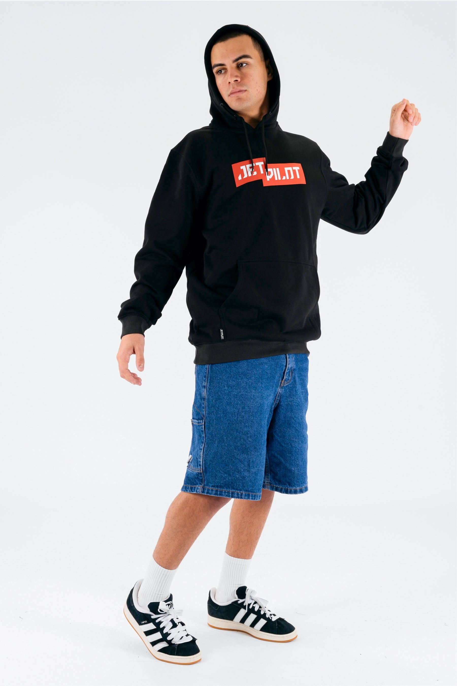 Side view of a person wearing a black pullover with a red Jetpilot logo on a white background — view 4 (3)