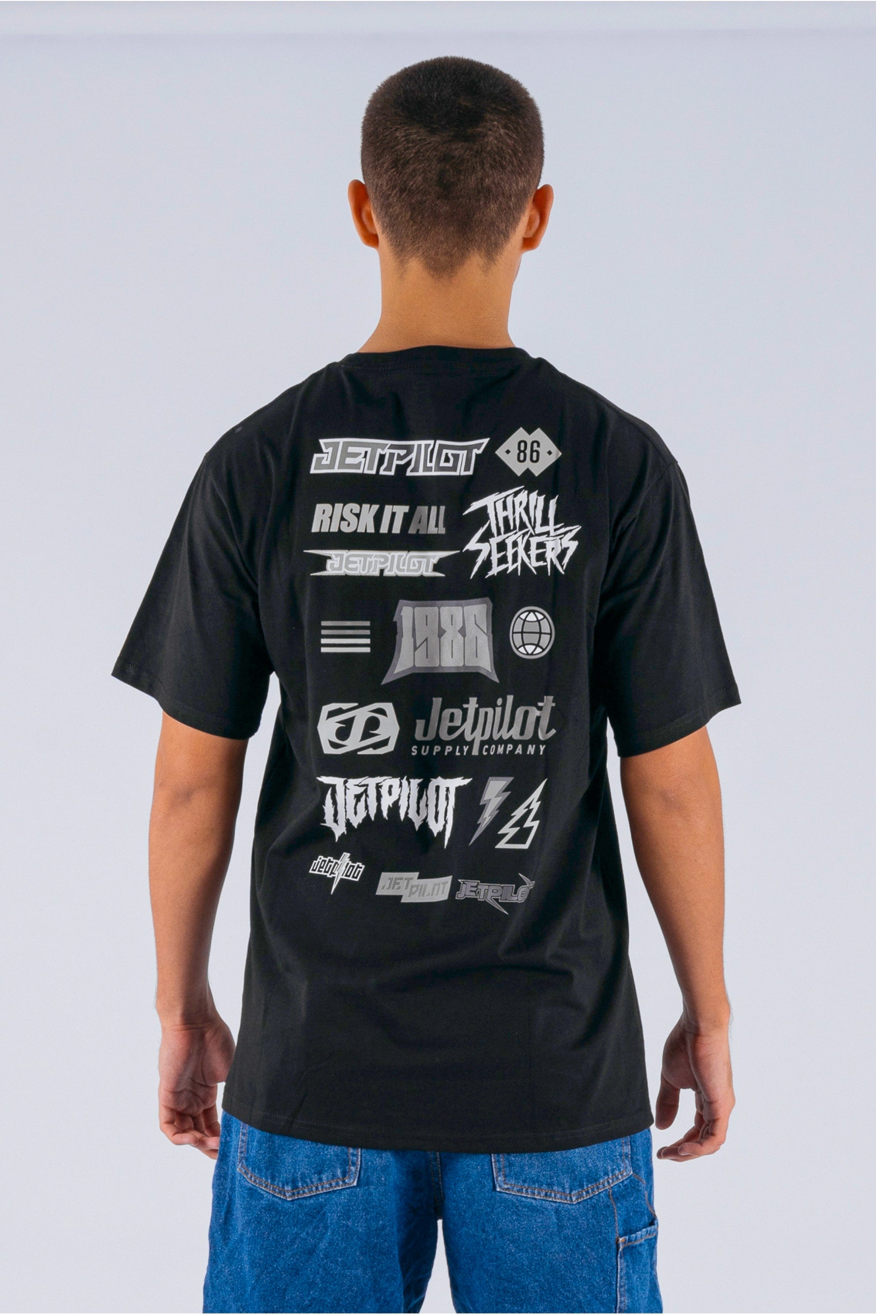 Back view of a person wearing a black tee with Jetpilot logos on a white background — view 2 (3)