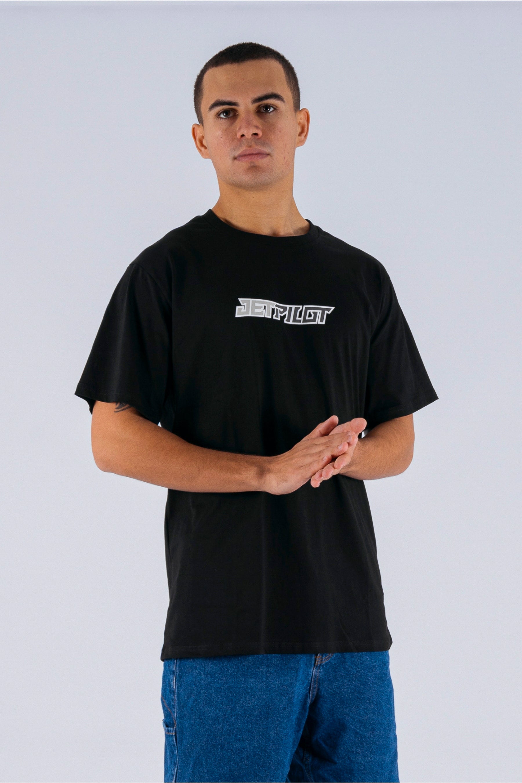 A person wearing a black tee with a Jetpilot logo on a white background — view 4 (5)