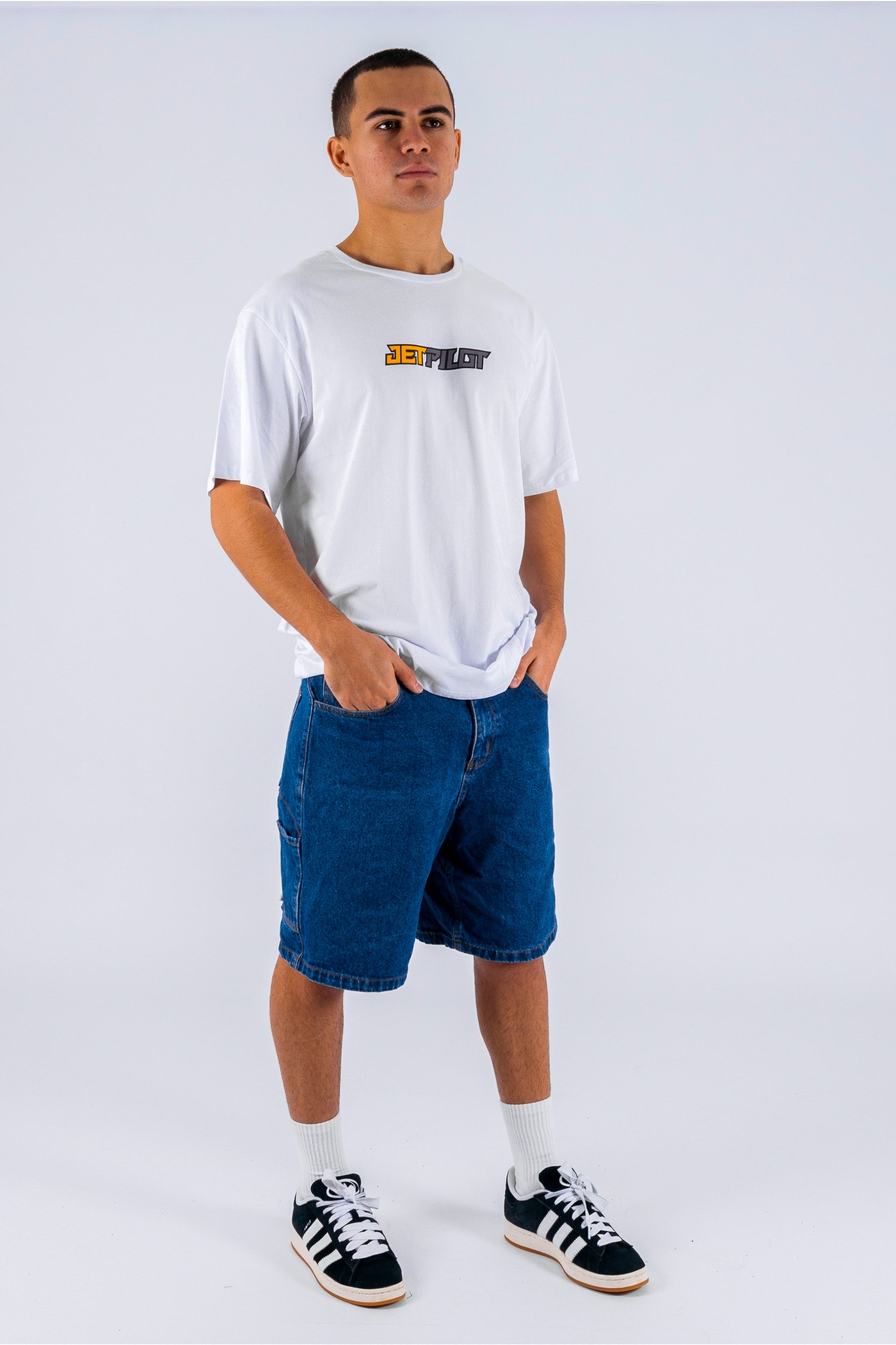 a person wearing a white tee, blue shorts and black/white shoes on a white background — view 4 (3)