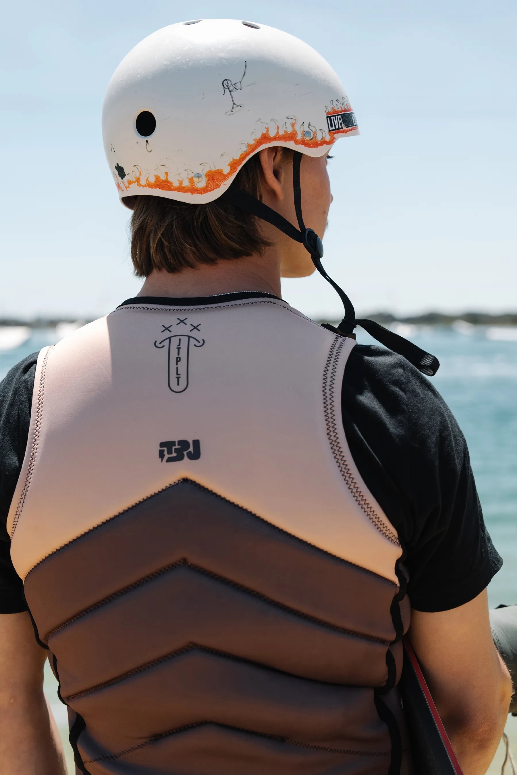 Person wearing a helmet and Jetpilot X1 Life Jacket - JTPLT X Heatley - Brown by the water
