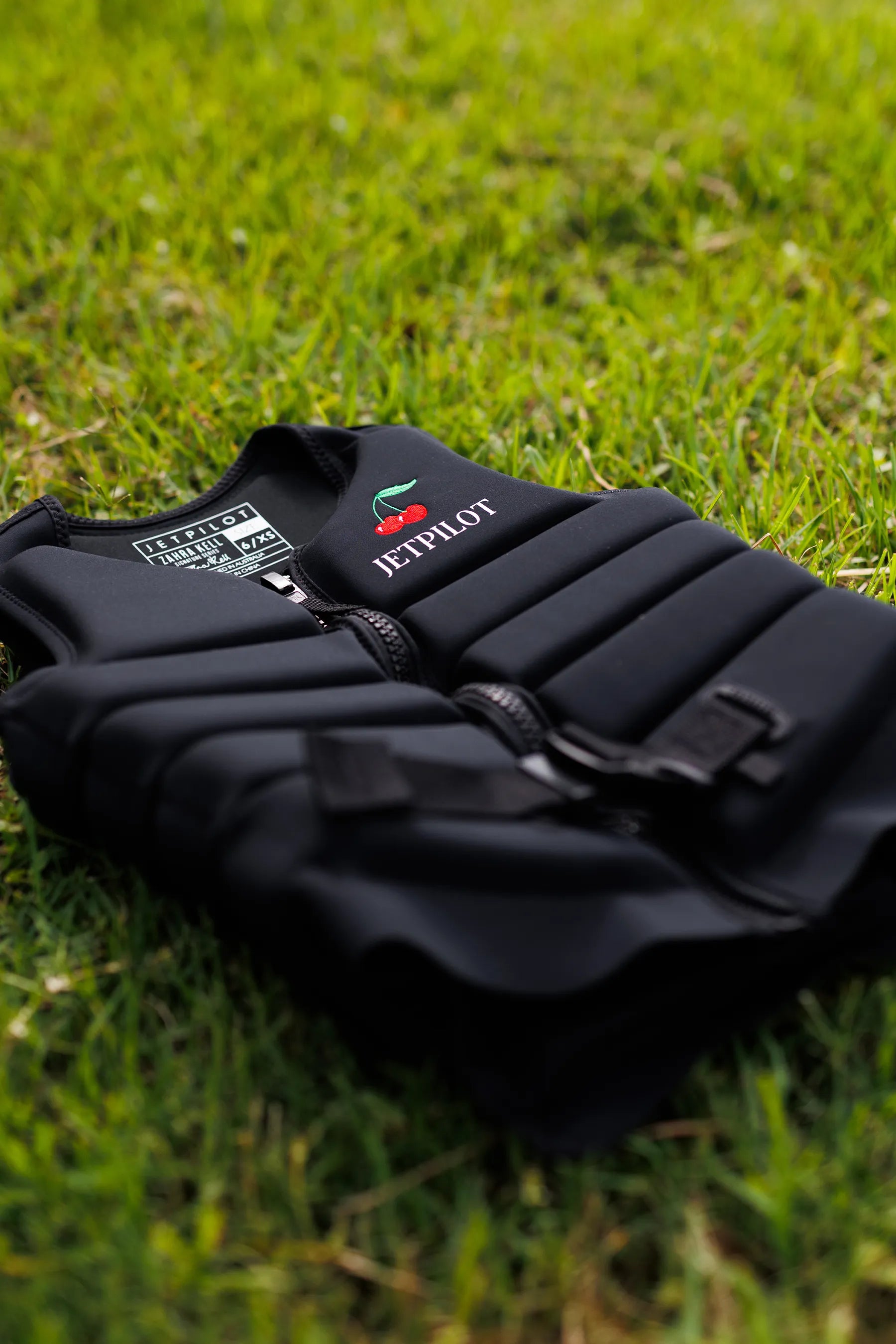 Jetpilot X1 Ladies Life Jacket - Zahra Kell Signature Series - Black with 'Jetpilot' logo on grass
