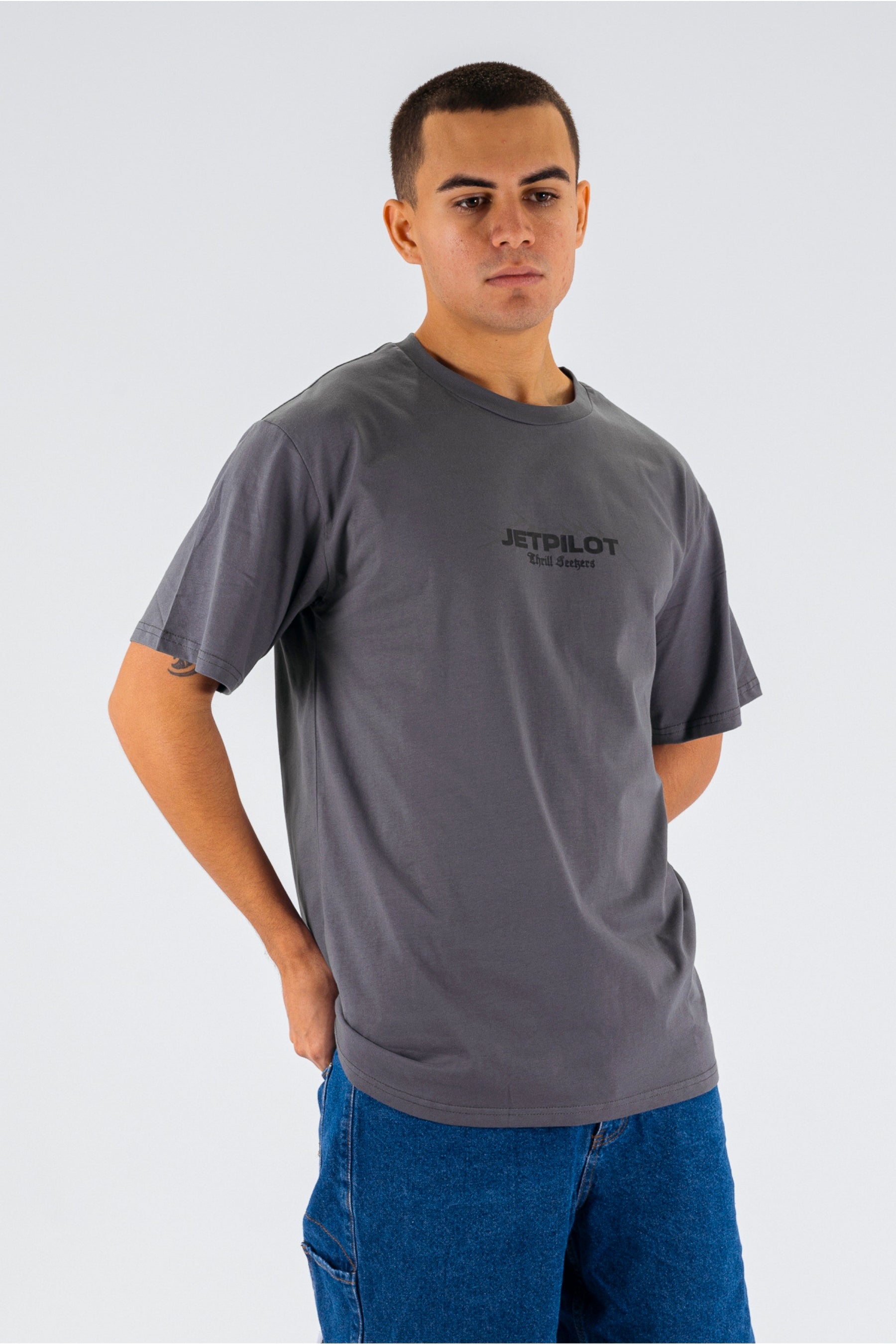 Front/side view of a person wearing a charcoal tee with a black Jetpilot logo on a white background — view 4 (3)