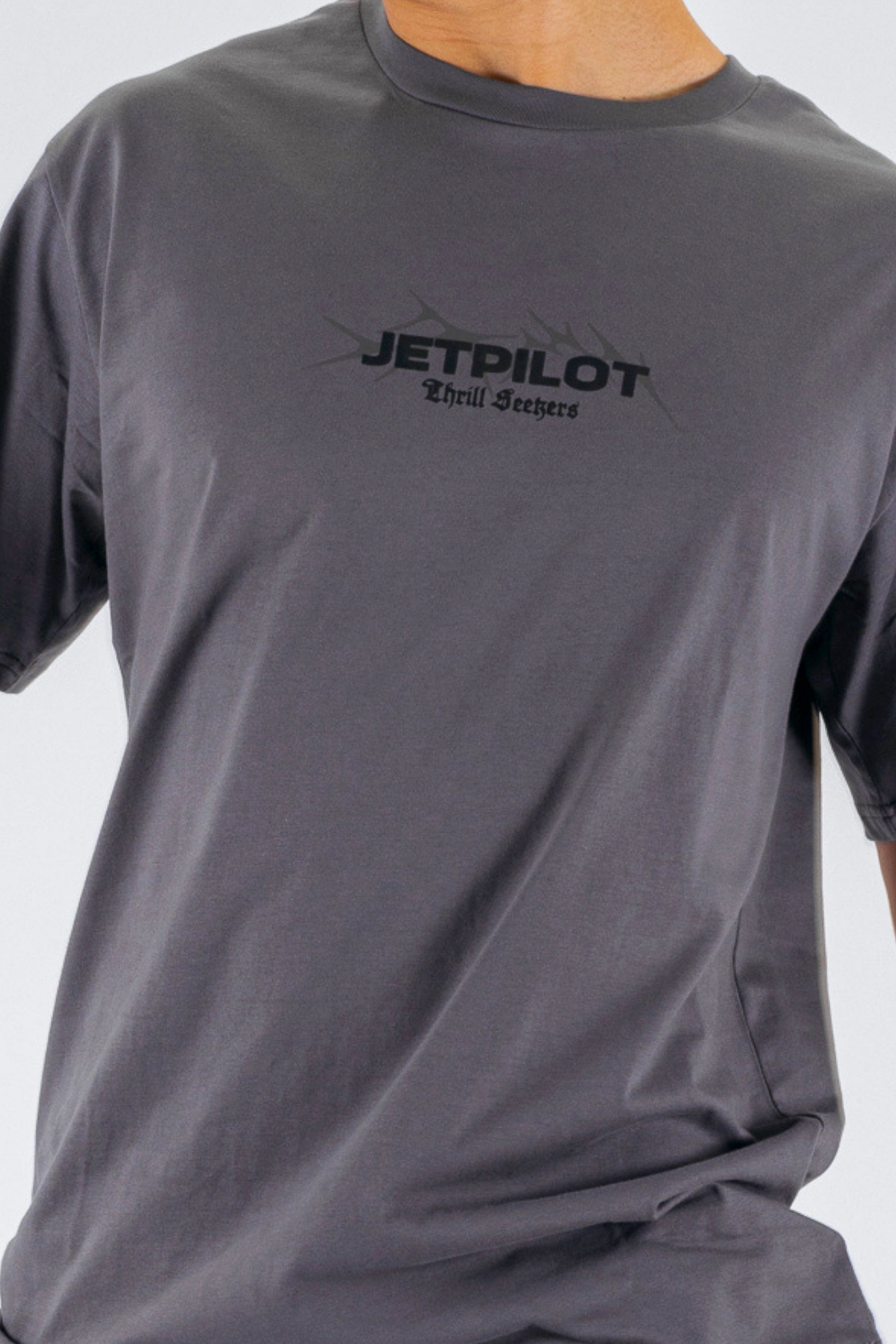 Close up of a person wearing a charcoal tee with a black Jetpilot logo on a white background — view 5 (3)