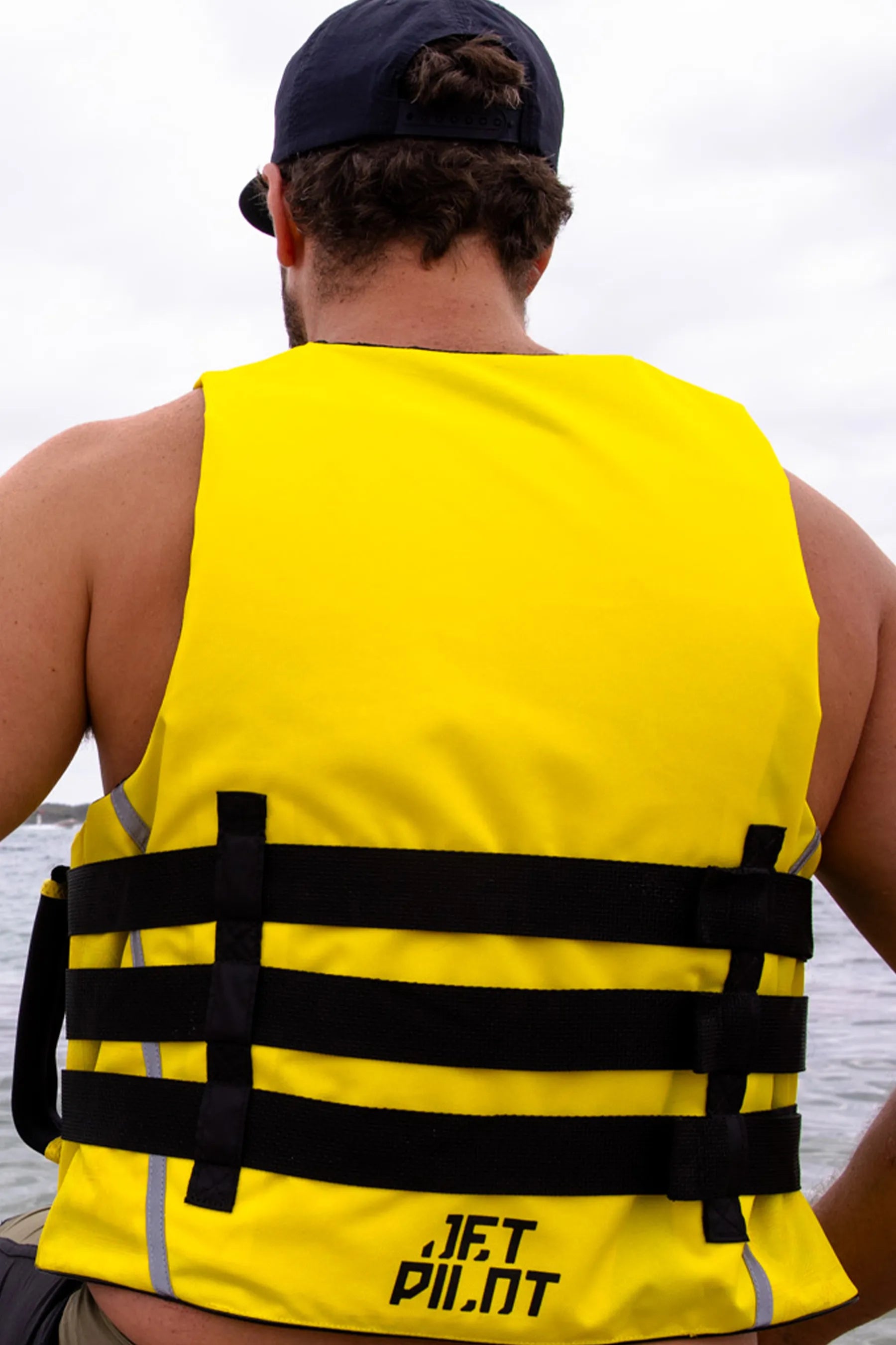 Person wearing a yellow life jacket with black straps outdoors