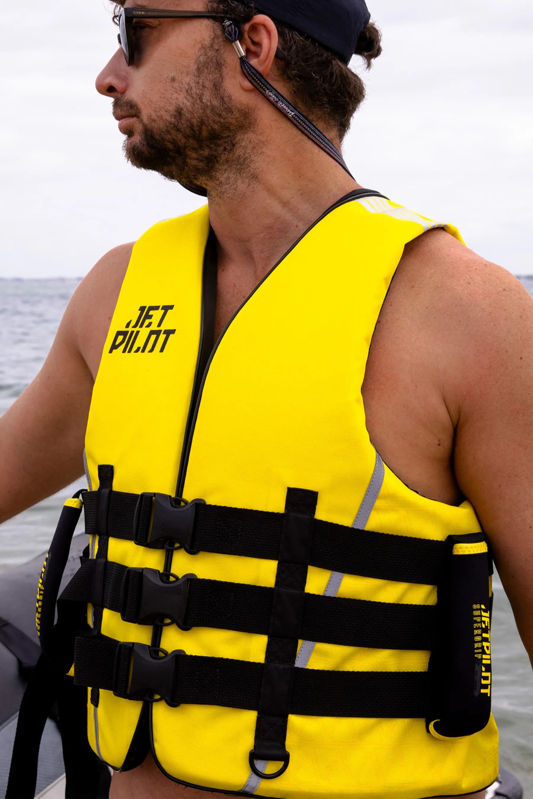 Man wearing a Jetpilot Titan Nylon Life Jacket - Black/Yellowwith 'Jetpilot' branding on a boat.