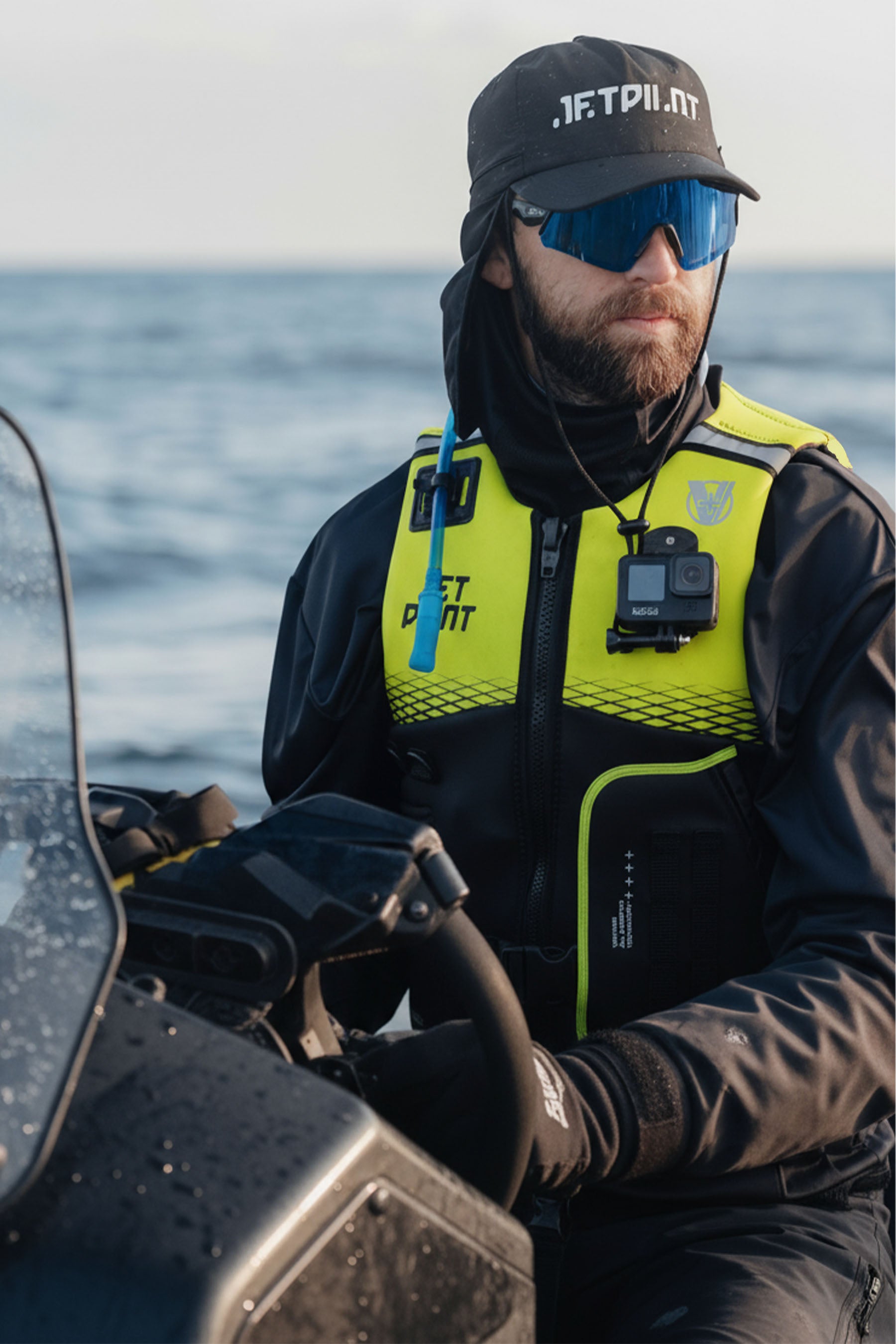 Person wearing a high-visibility life vest and sunglasses on a boat with water in the background