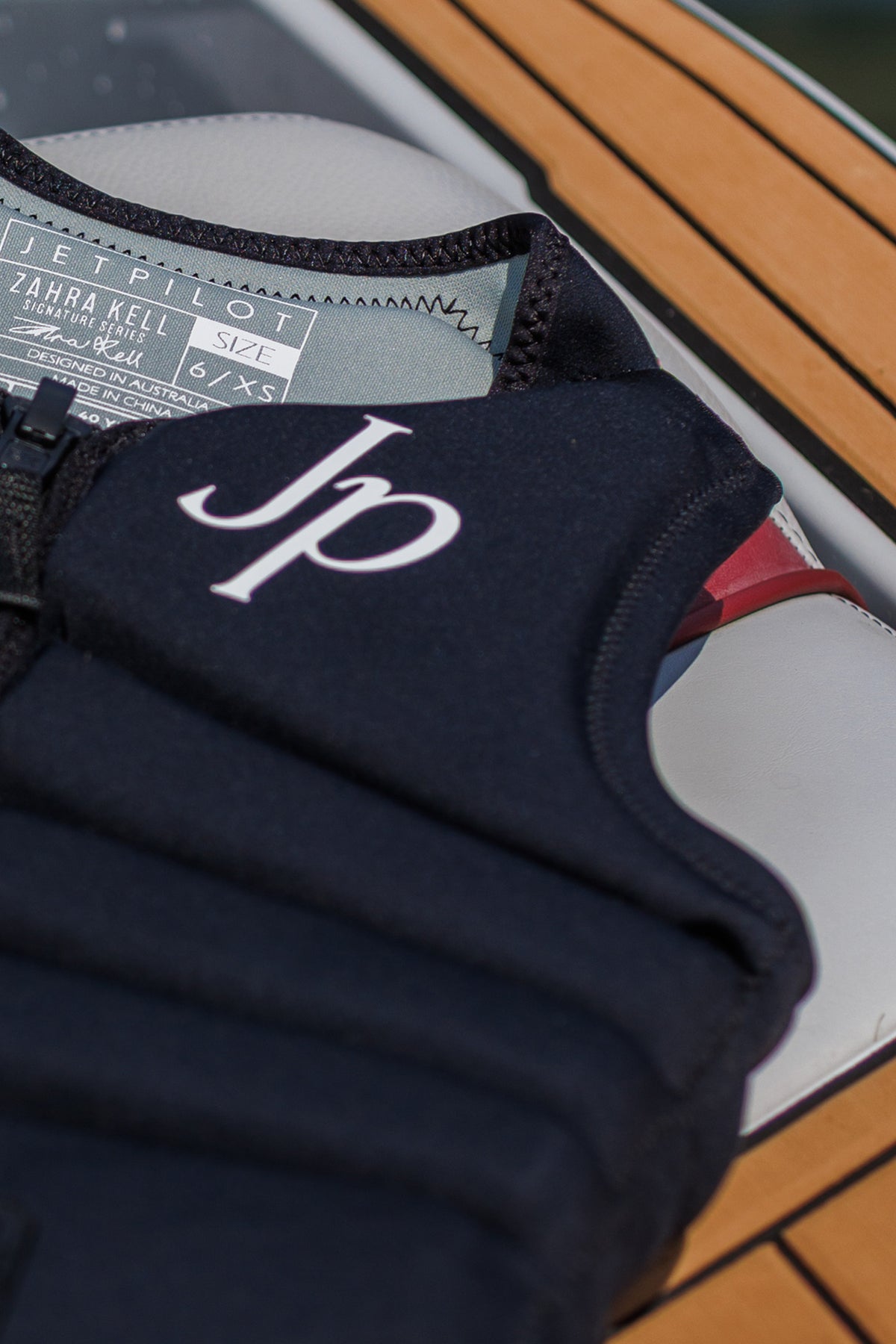 Black Zahra X1 lying on a boat seat, close-up of the white Jp monogram and collar